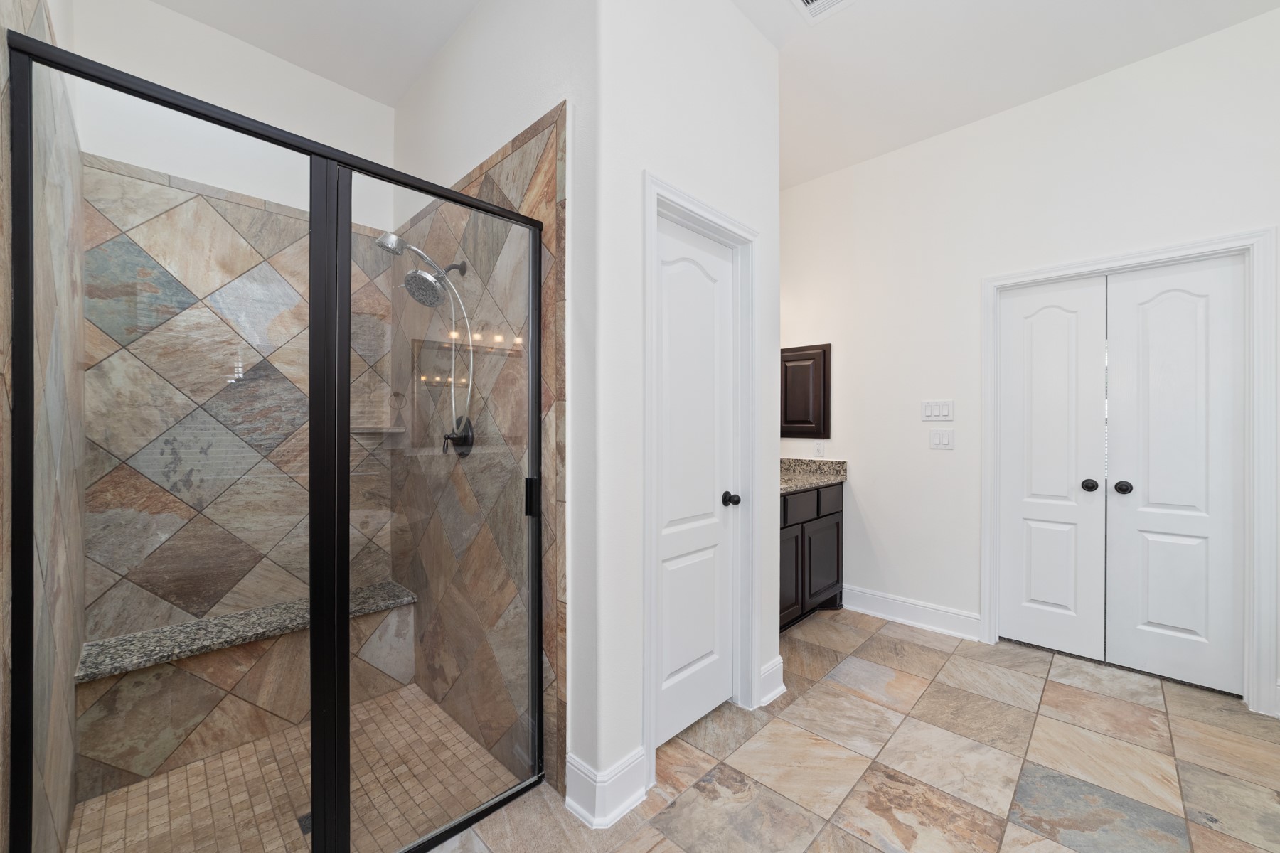This modern bathroom features a tiled walk-in shower with glass doors.