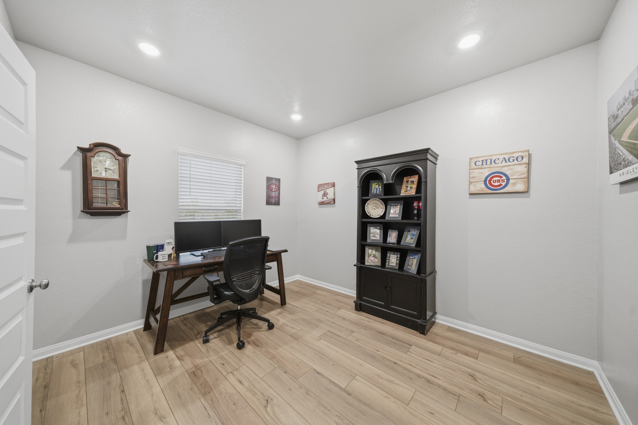 Bright and inviting home office featuring modern recessed lighting, warm vinyl plank wood-look floors, and a stylish workspace.