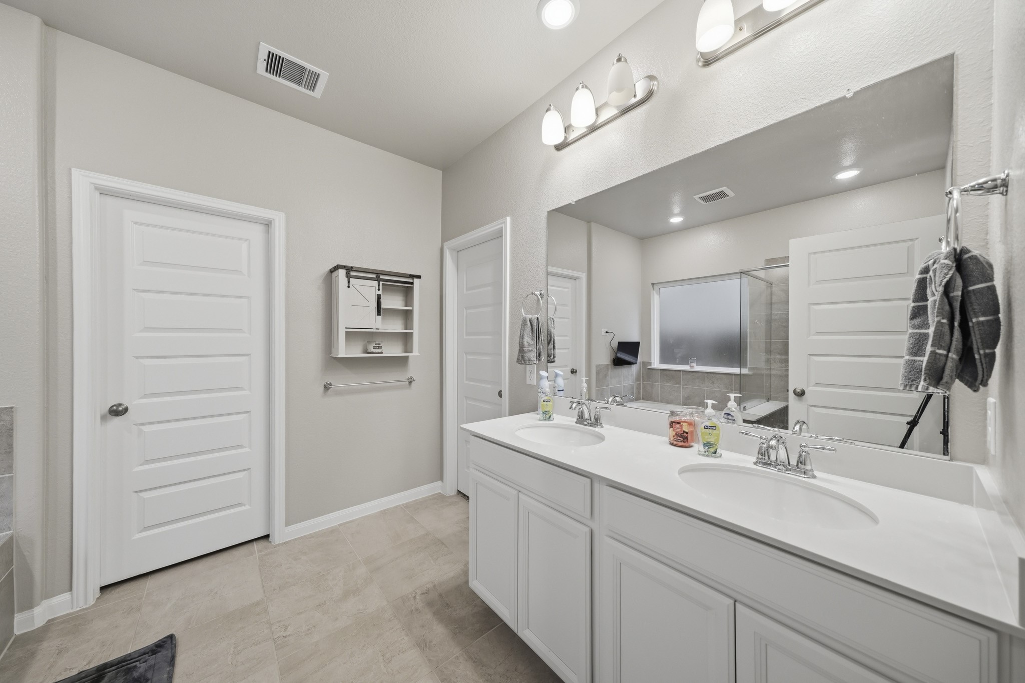 Spacious and modern bathroom featuring a double vanity with sleek fixtures, ample counter space, and a large mirror.