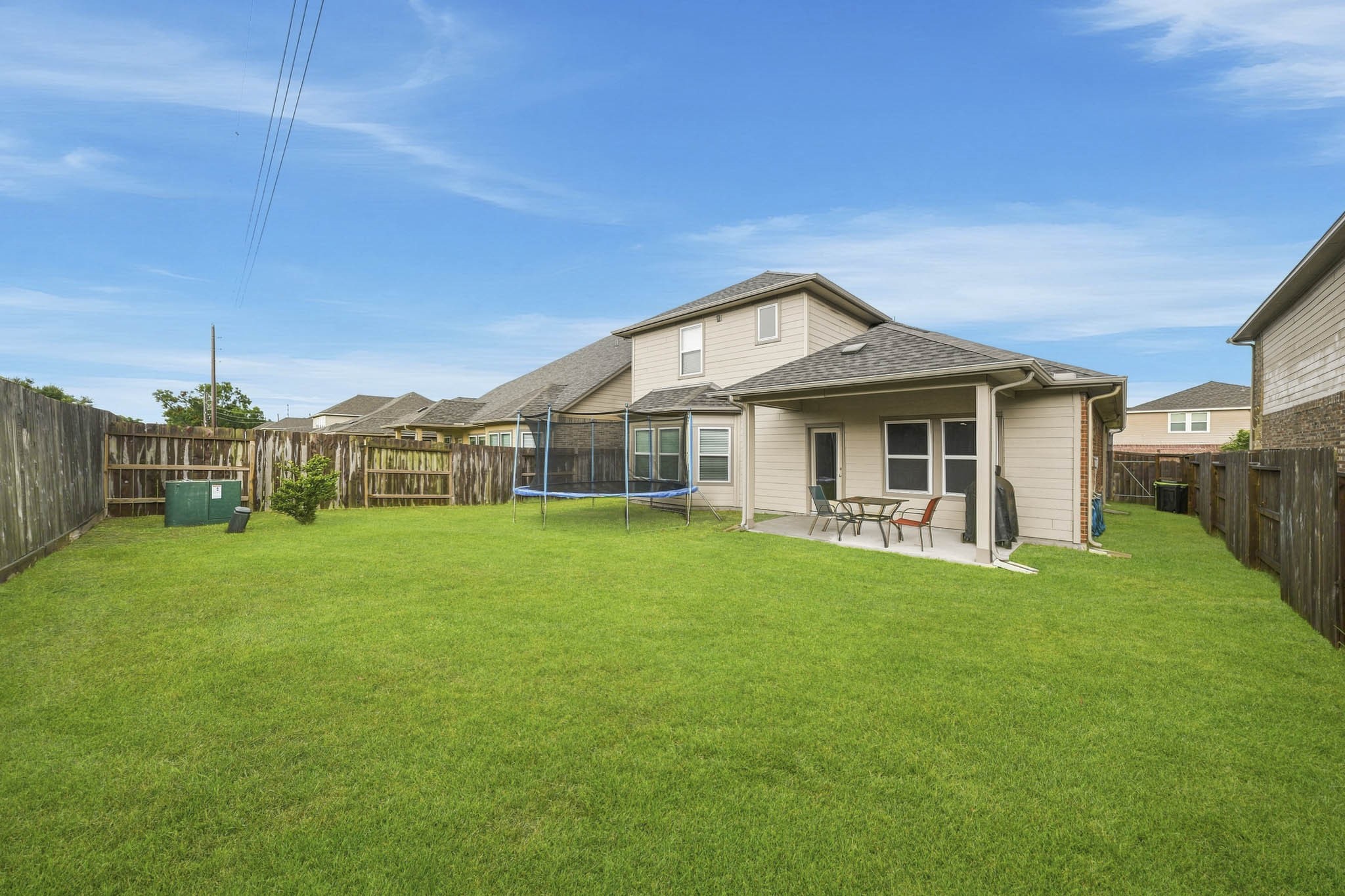 Spacious fenced backyard with a covered patio, perfect for outdoor gatherings and relaxation.