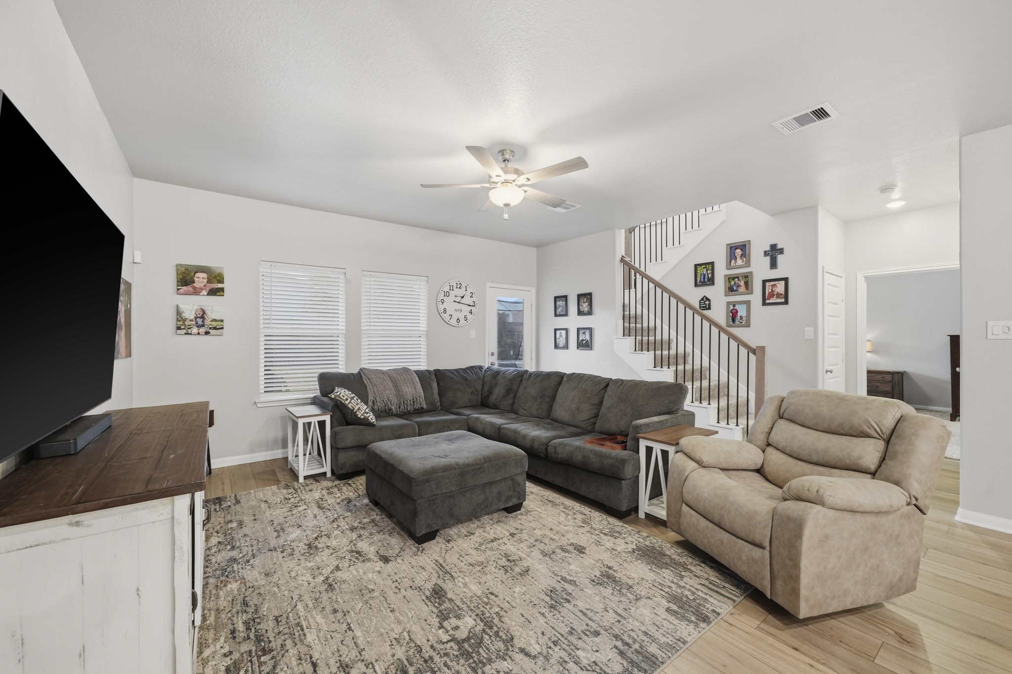 Another view of the spacious living room with a cozy sectional sofa, plush recliner, and a large TV, perfect for relaxing.