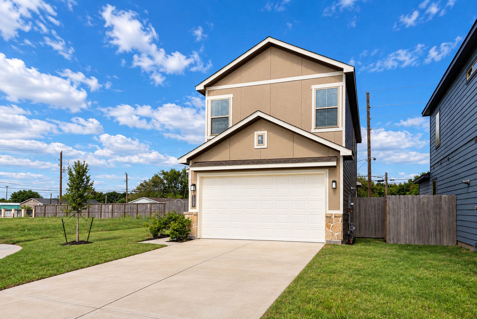 From this angle you can see how the stone-accented garage and the neutral exterior palette balance the home's two-story lines. The side fence adds privacy along the property edge, and the sidewalk and driveway make coming and going effortless. It is a clean, move-in-ready exterior with low-maintenance cement board and stucco, so weekends can be spent enjoying the neighborhood instead of upkeep.