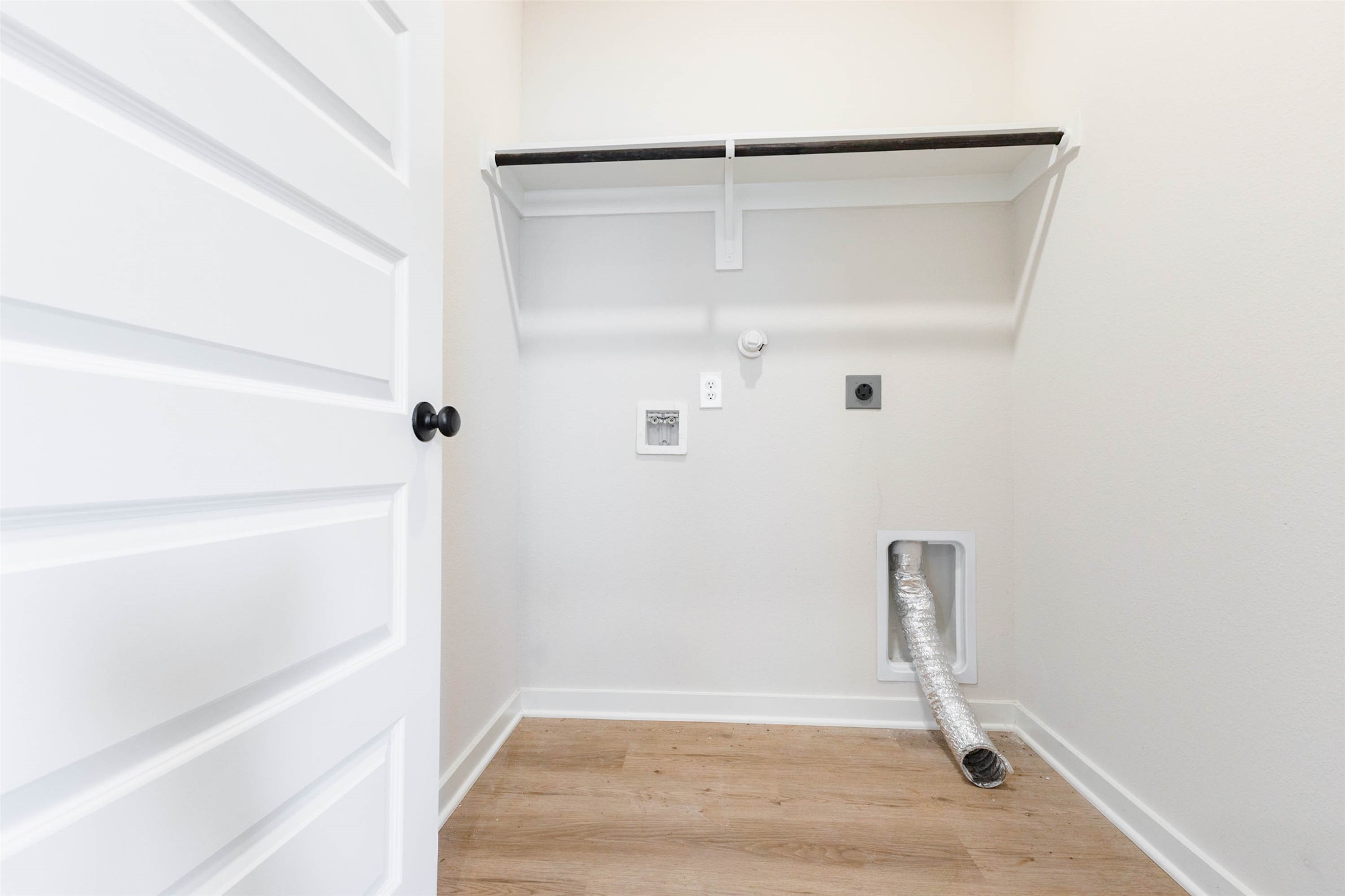 The laundry room is thoughtfully equipped with washer connections, electric and gas dryer hookups, a dryer vent and a wall shelf with hanging rod for drying delicates or storing supplies. Wood-look flooring continues here and a full-size door keeps noise out of the living area. Everything you need for laundry day is right at hand, making it a smart, convenient feature.