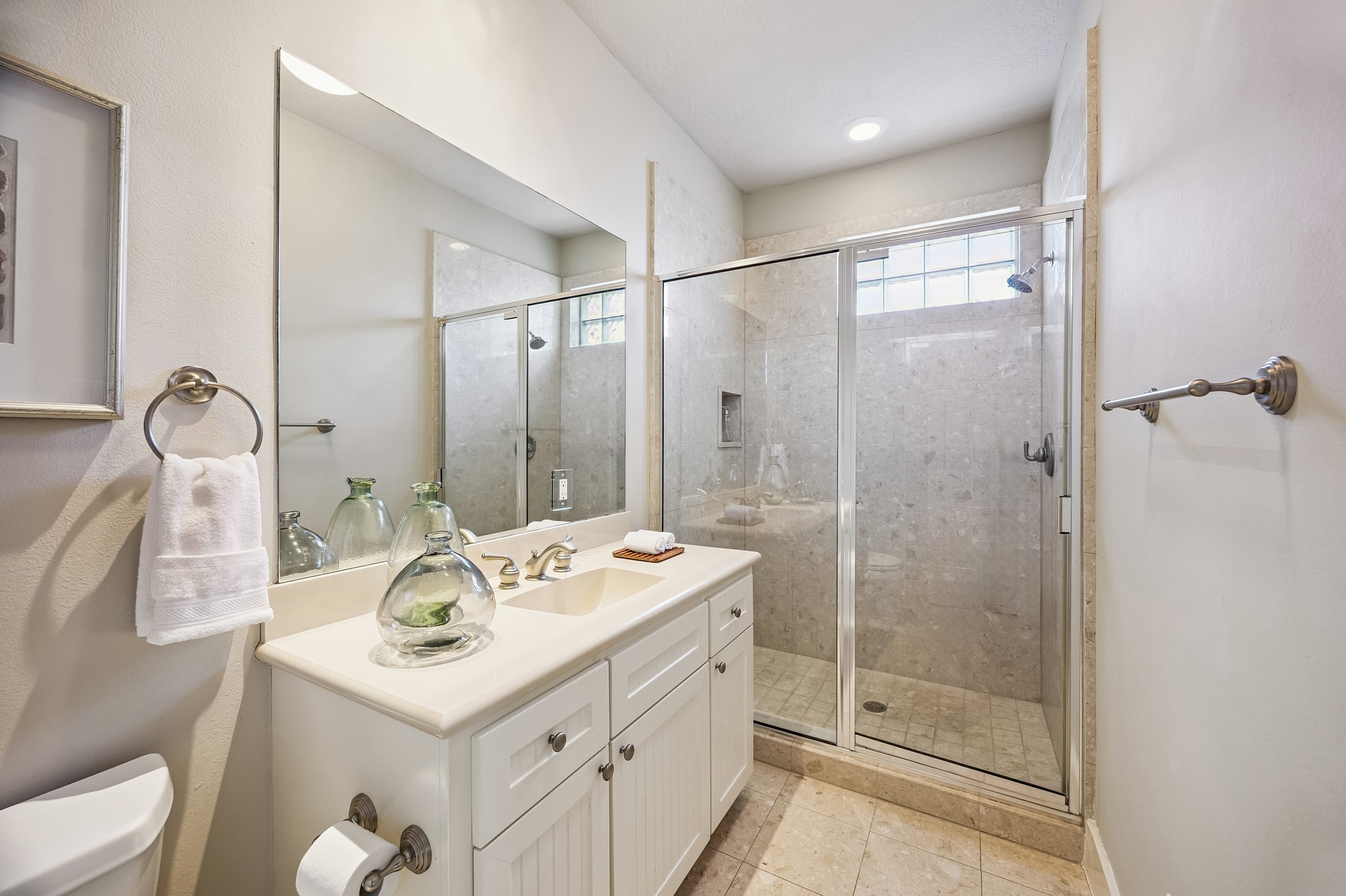 The full ensuite bath serving the first-floor bedroom features a glass enclosed walk-in shower.