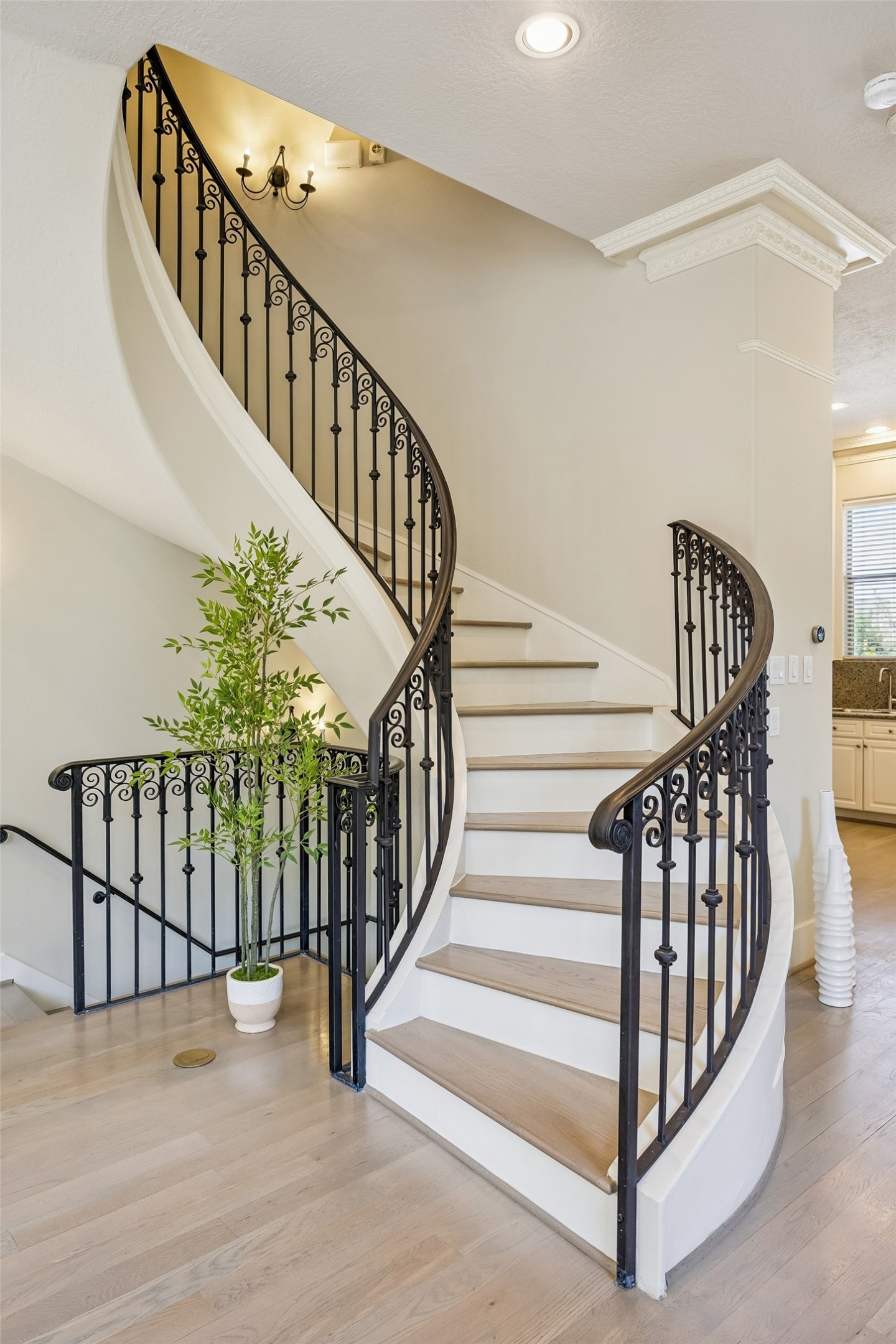 Beautiful curved staircase with iron banister creates an architectural focal point in the main living area.