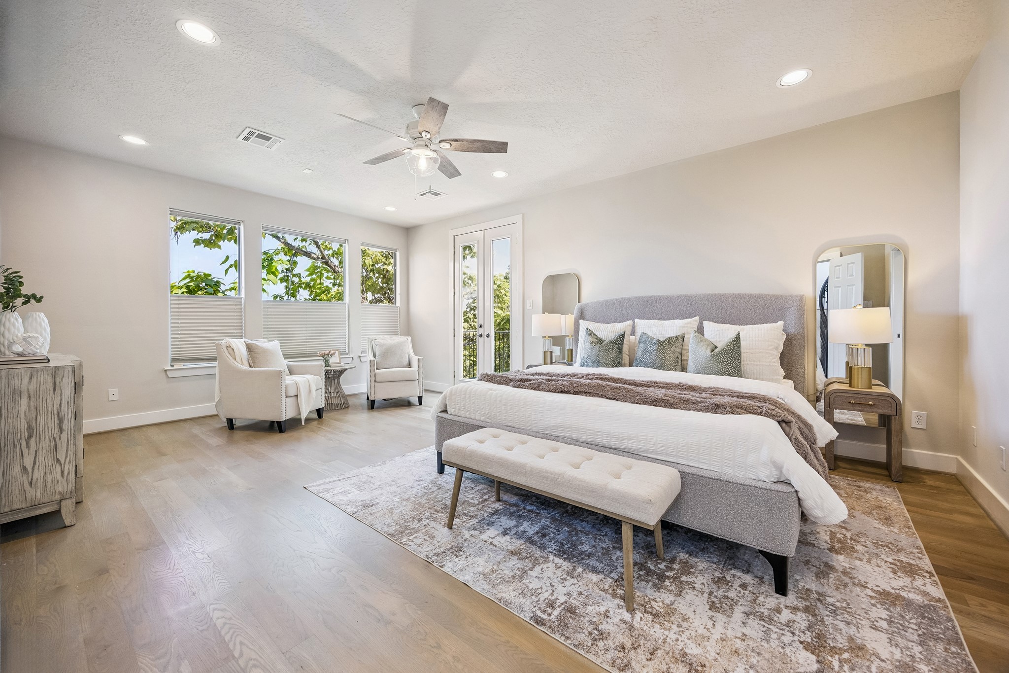 Spacious primary suite with hardwood flooring, multiple windows and private balcony access.
