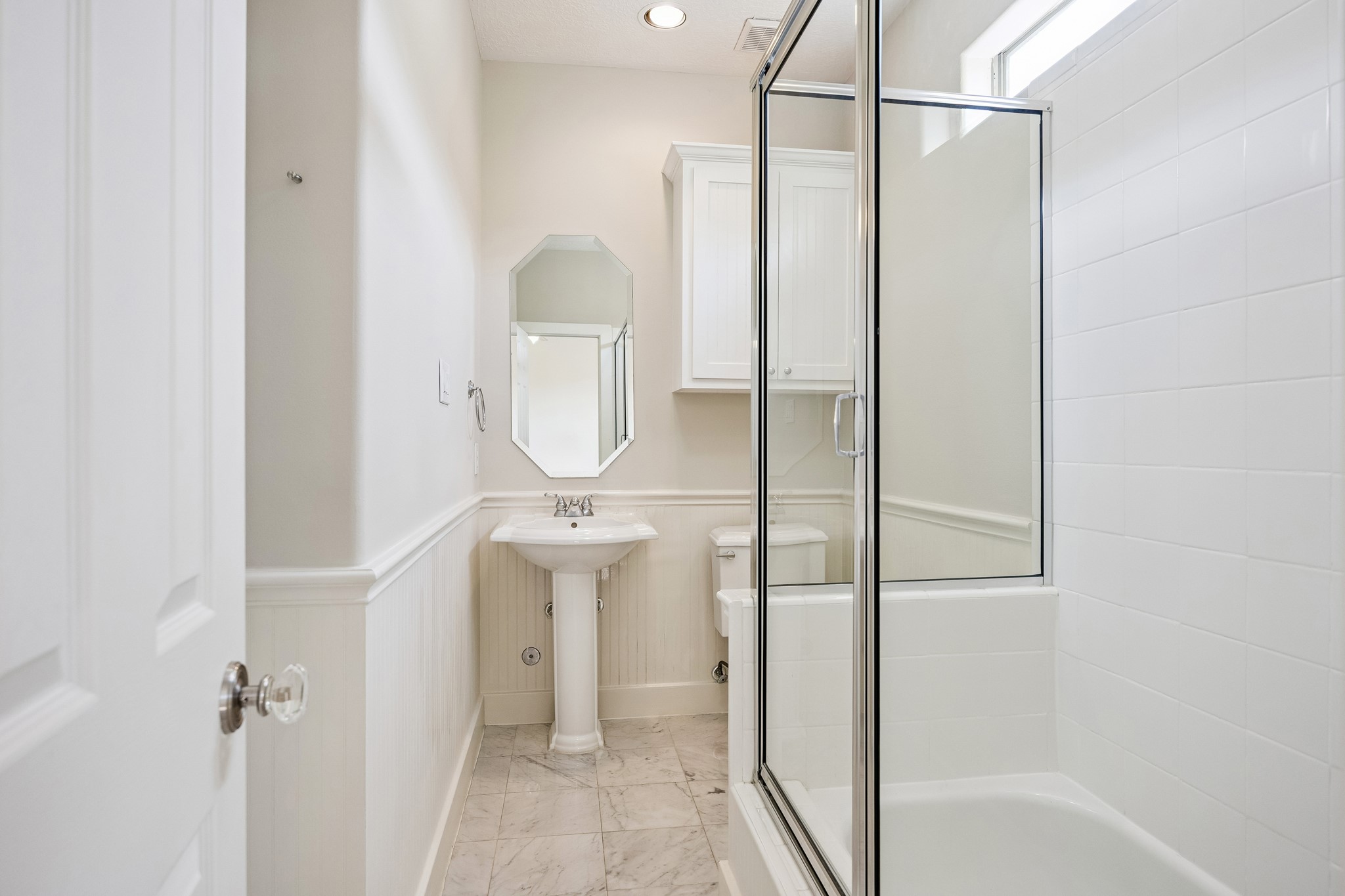 En-suite secondary bath with a glass enclosed tub/shower combination.