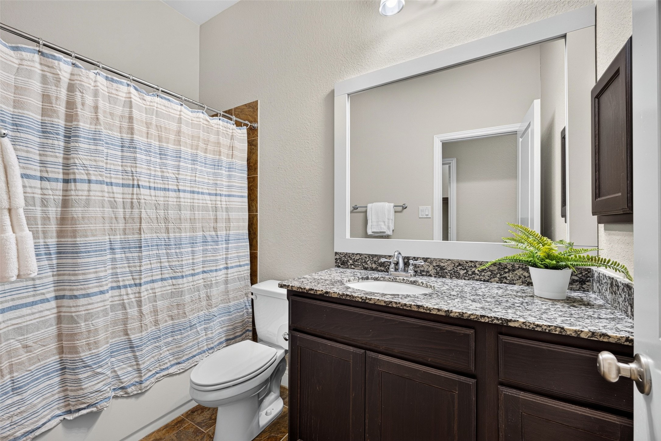 Clean and sparkling guest bathroom equipped with ample vanity storage and quality finishes.