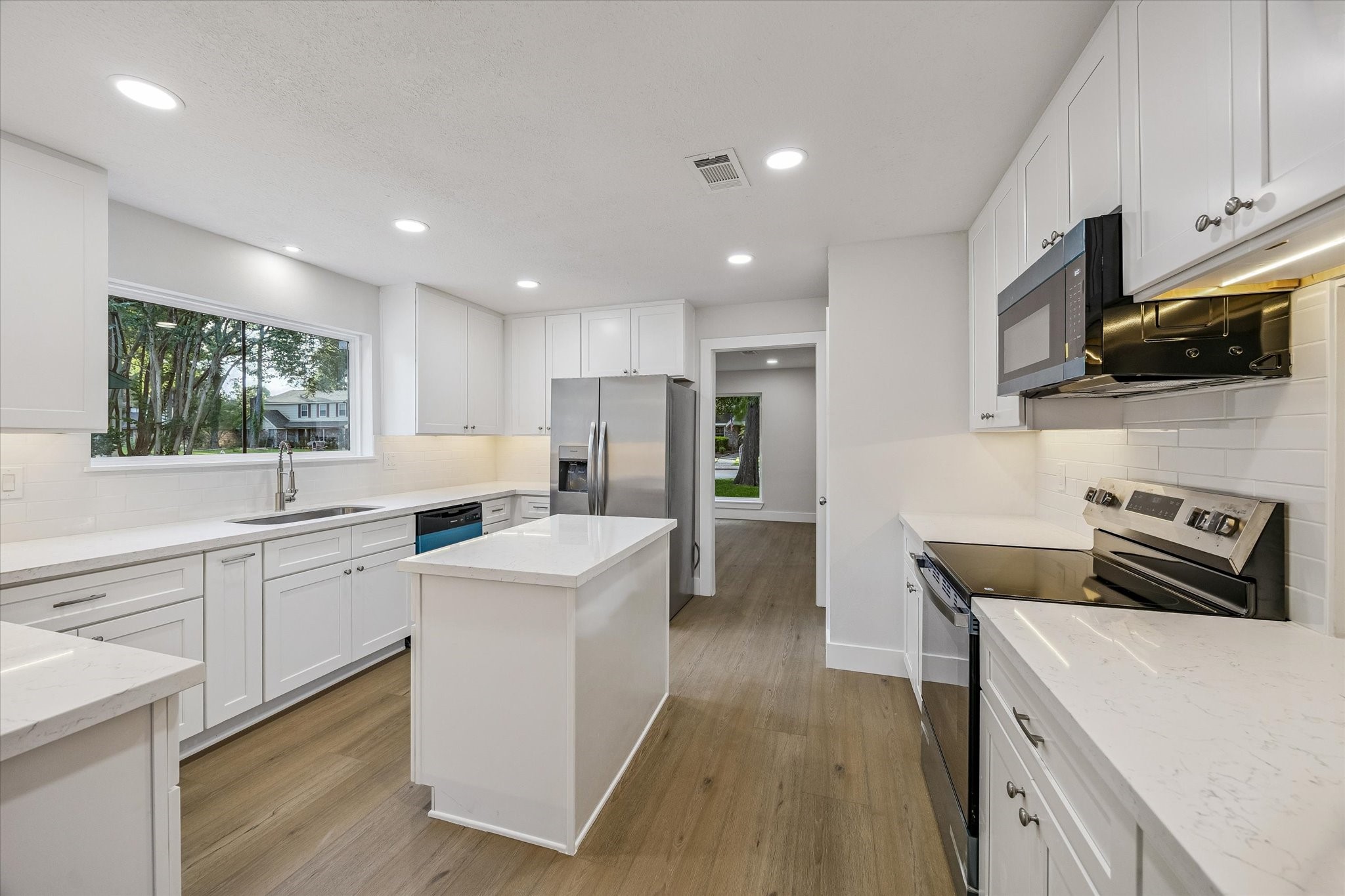 Fully renovated chef's kitchen featuring under cabinet lighting, new white shaker cabinetry, new hardware and fixtures, LED recessed lighting, and brand new stainless steel appliances  refrigerator included.