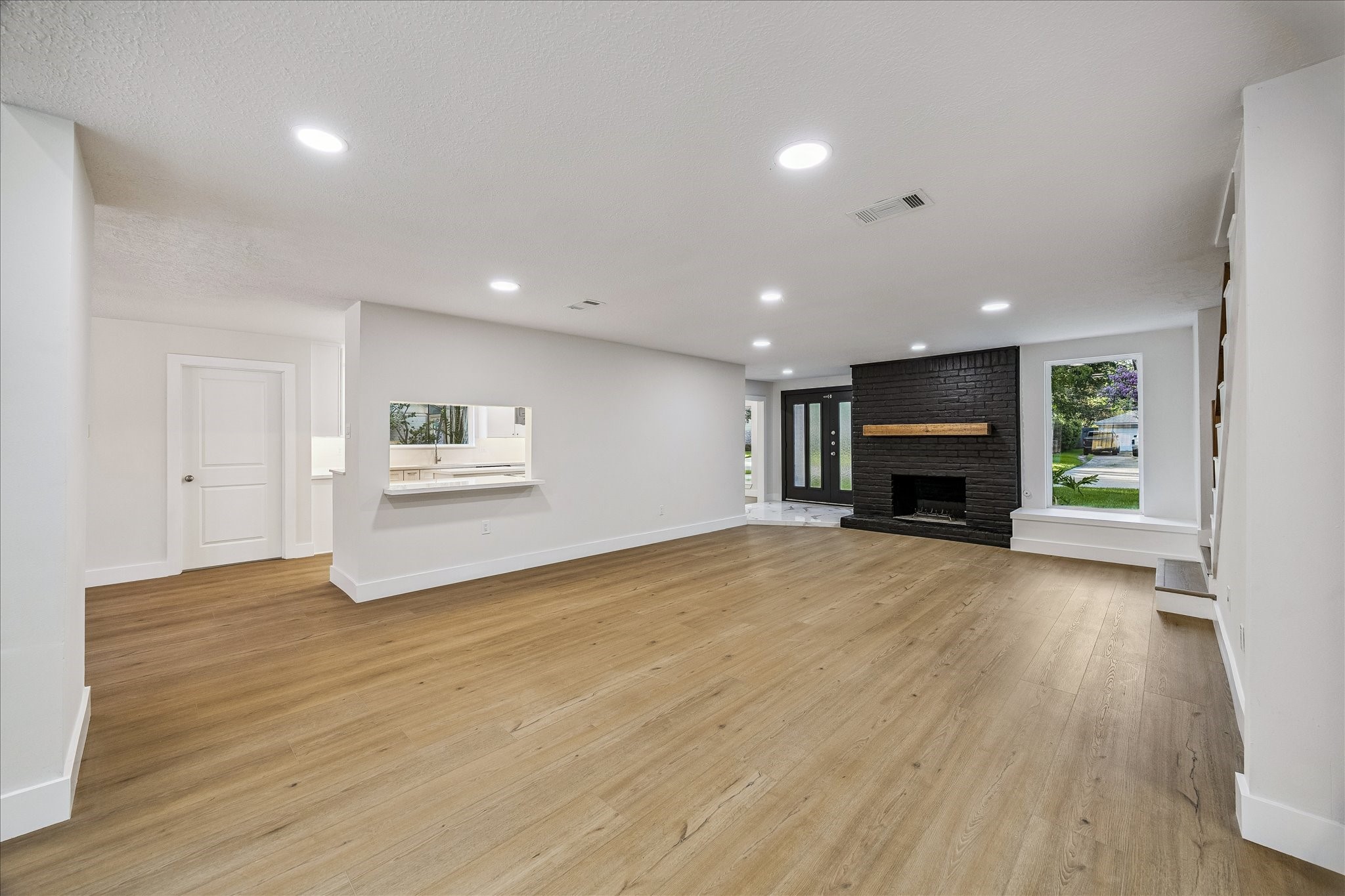 Living room just off the kitchen. original gas-log fireplace with matte black brick hearth. sitting nook near windows.