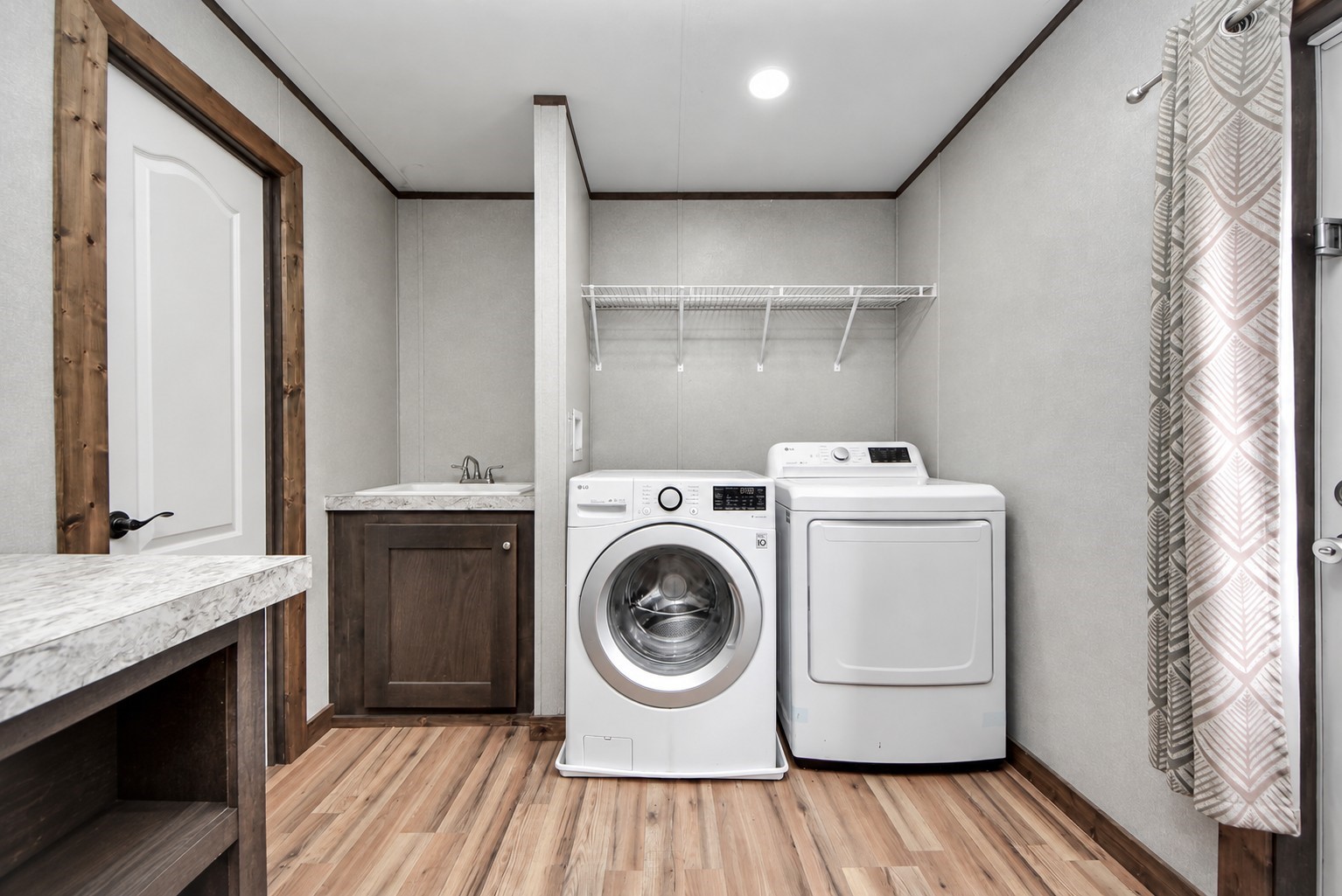 Laundry room showcasing a side utility sink and overhead sheliving.
