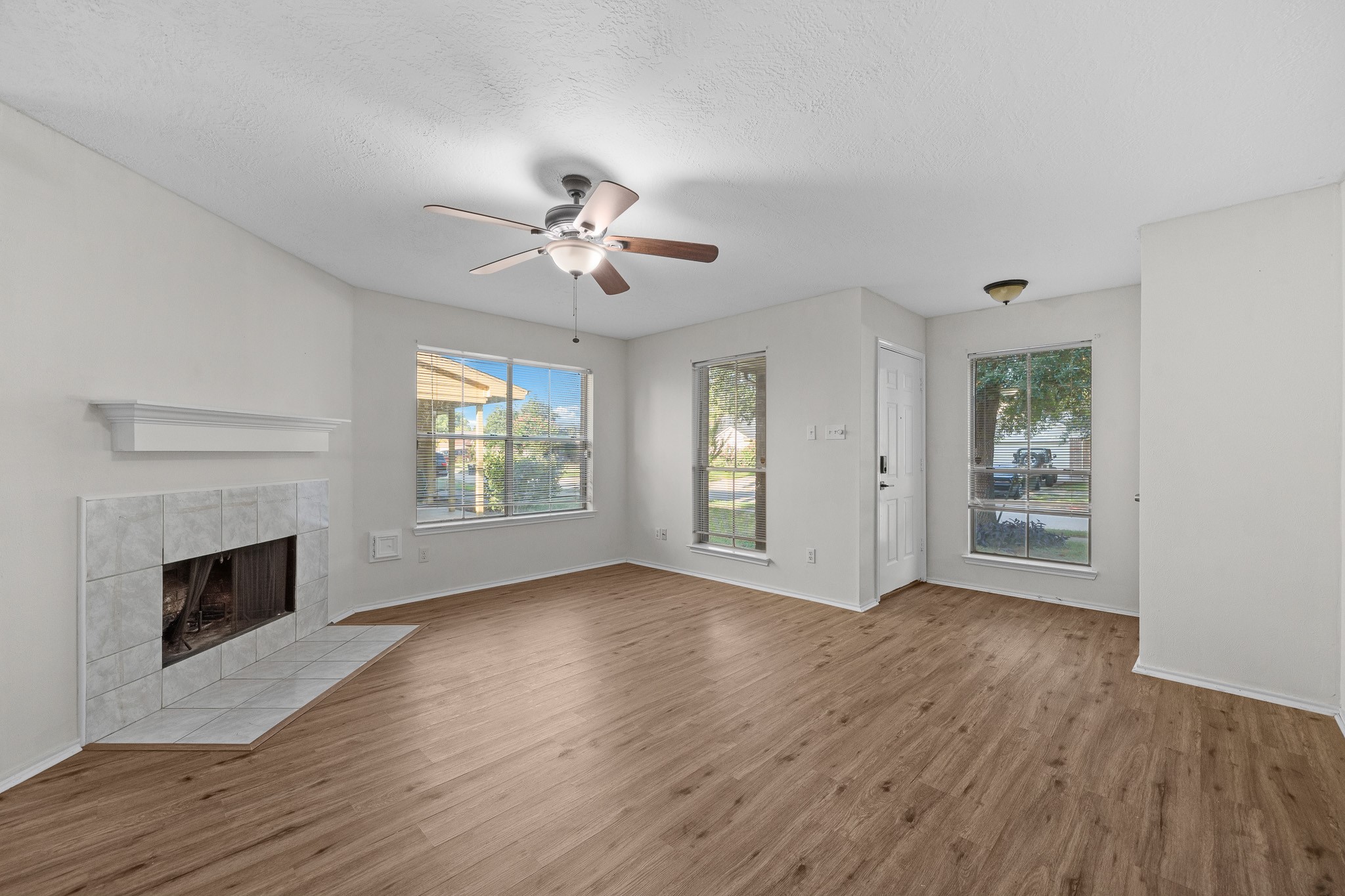 Bright and inviting living room featuring a cozy fireplace, elegant flooring, and large windows that offer plenty of natural light.