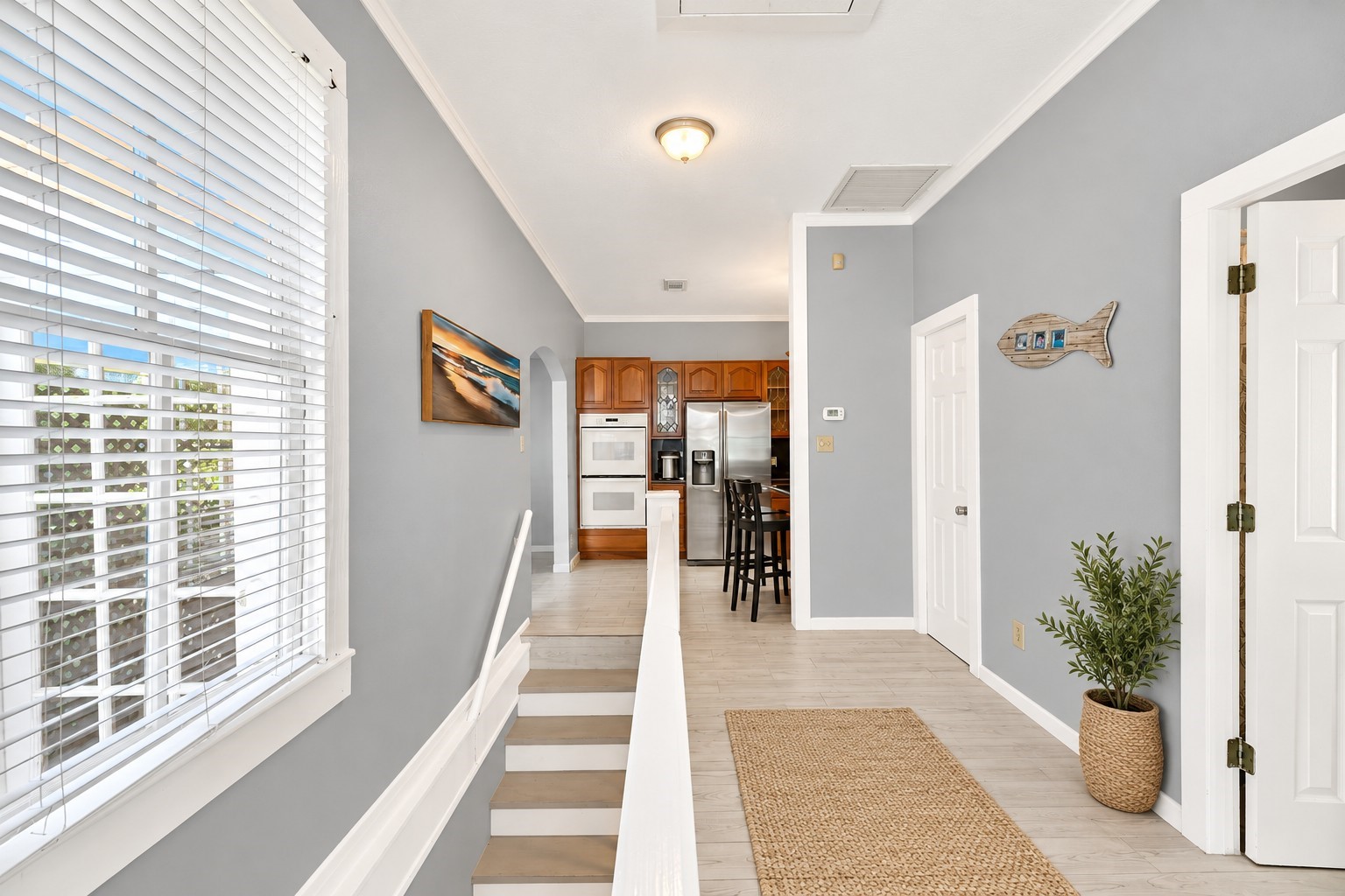Bright and inviting stairwell leading to the second-floor hallway that features natural light, and coastal-inspired finishes. Conveniently connects the upstairs kitchen, dining, and living areas, while the staircase also provides access to the first-floor entry and two downstairs bedrooms with a shared Jack-and-Jill bathroom. A practical two-level layout designed for comfortable coastal living.
