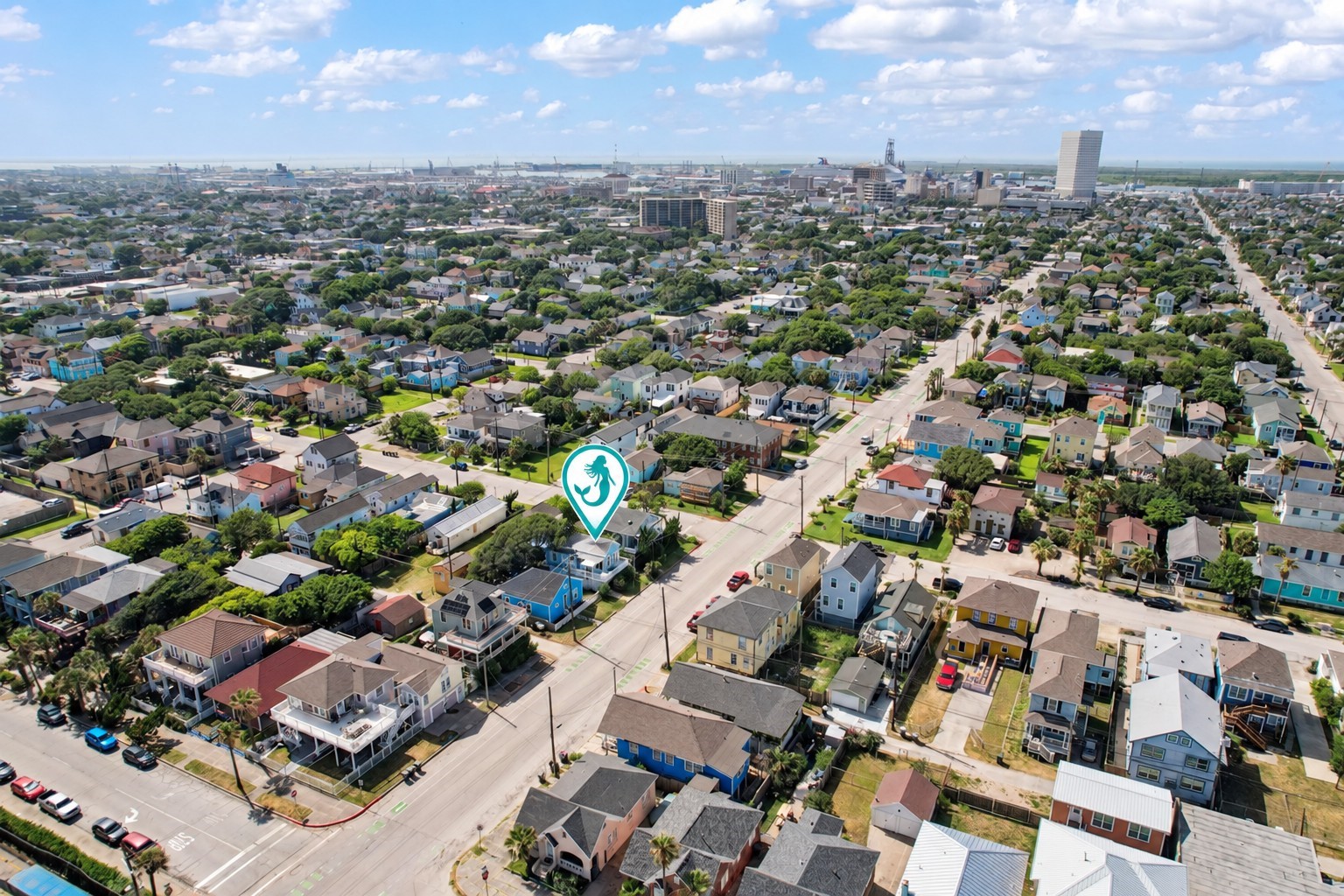 Aerial view highlighting the property's location among Galveston's charming coastal homes, with downtown Galveston and the Port of Galveston visible in the distance.