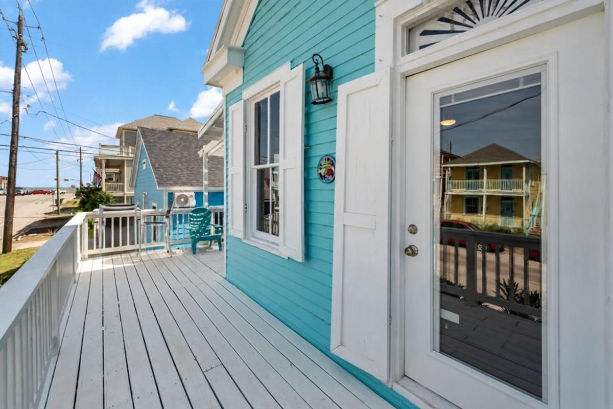 Second-Floor Deck: Enjoy coastal living from this inviting second-floor deck featuring vibrant turquoise siding, white railings, and outdoor seating. Conveniently accessible from the living area, this charming outdoor space offers views toward the Gulf and a relaxing setting to enjoy the coastal breeze, just approximately 1 blocks from the beach!