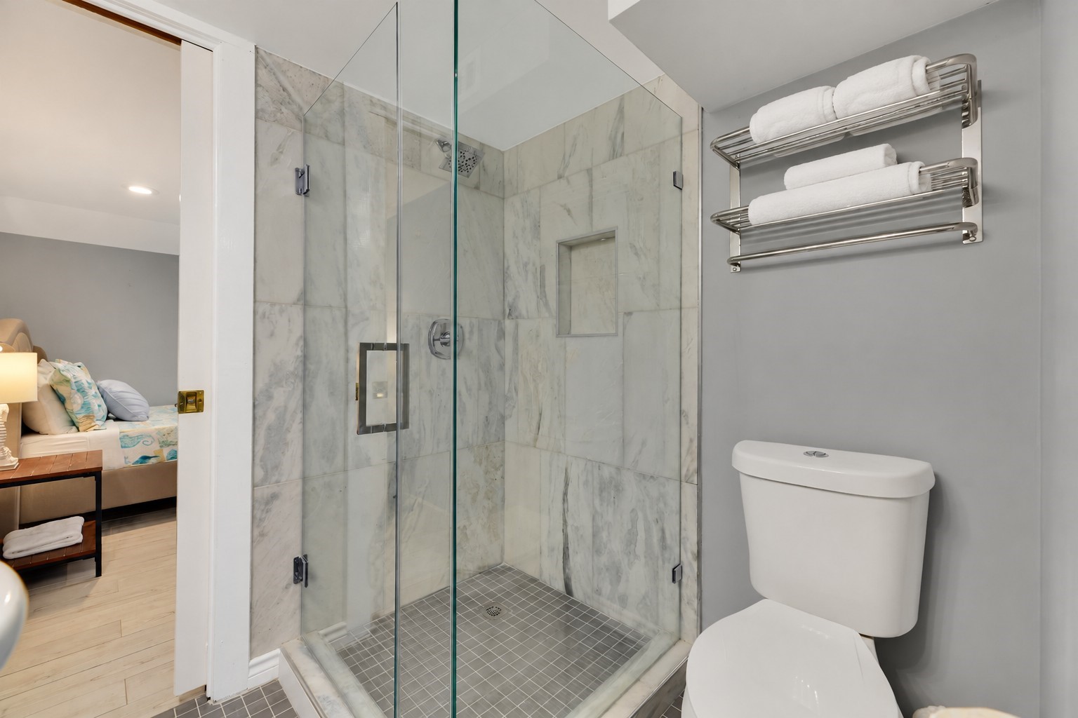 Beautifully appointed Jack-and-Jill bathroom connecting Bedrooms 1 and 2 on the first floor. Features a spacious walk-in shower with marble-look tile surround, frameless glass enclosure, rainfall-style showerhead, built-in shower niche, and modern finishes.