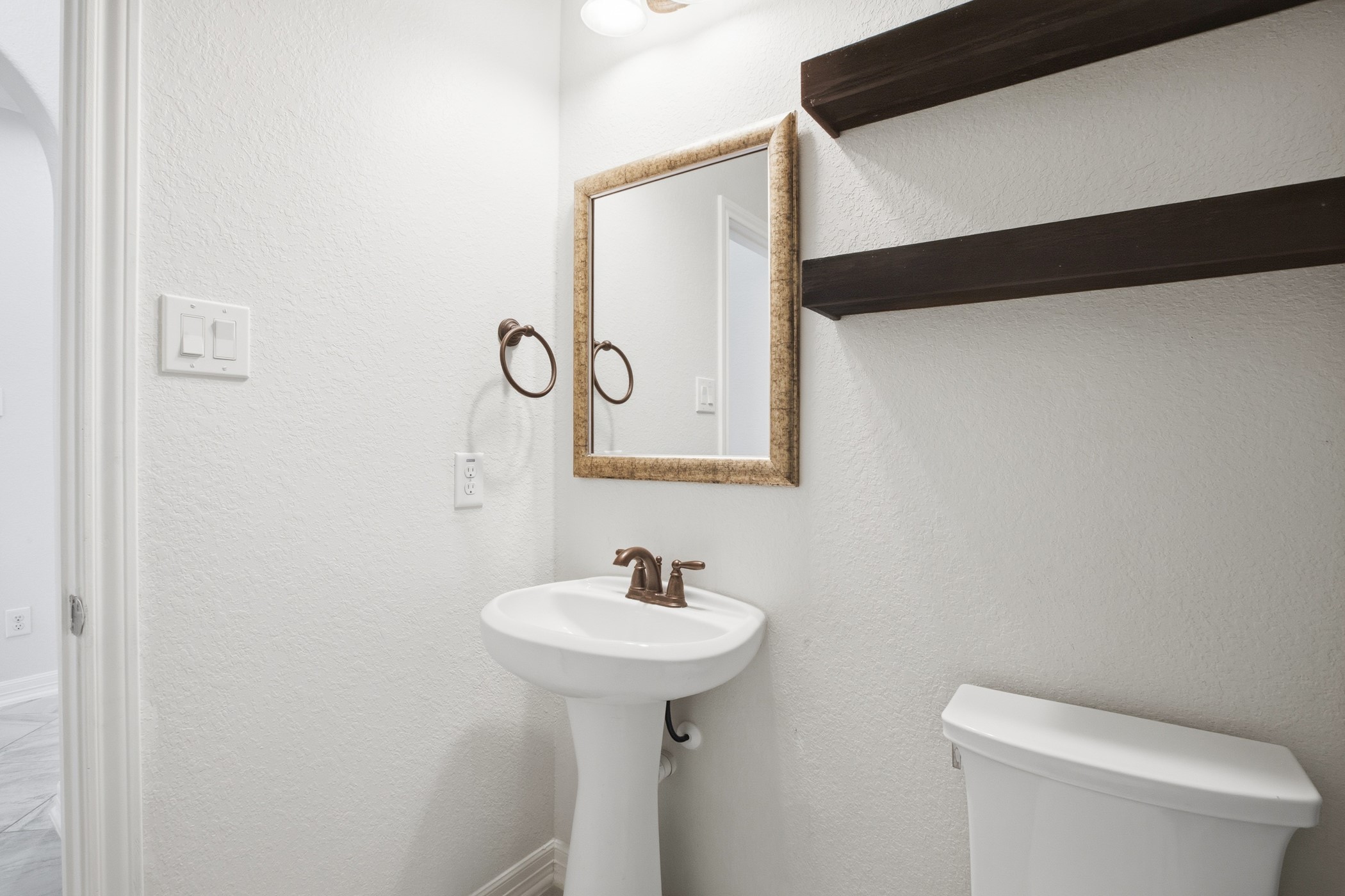 Half bathroom with floating shelves, located down stairs for guests