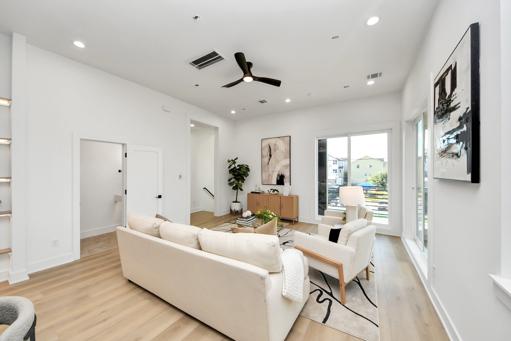 Bright living room featuring modern seating, oversized windows, and access to the private balcony.