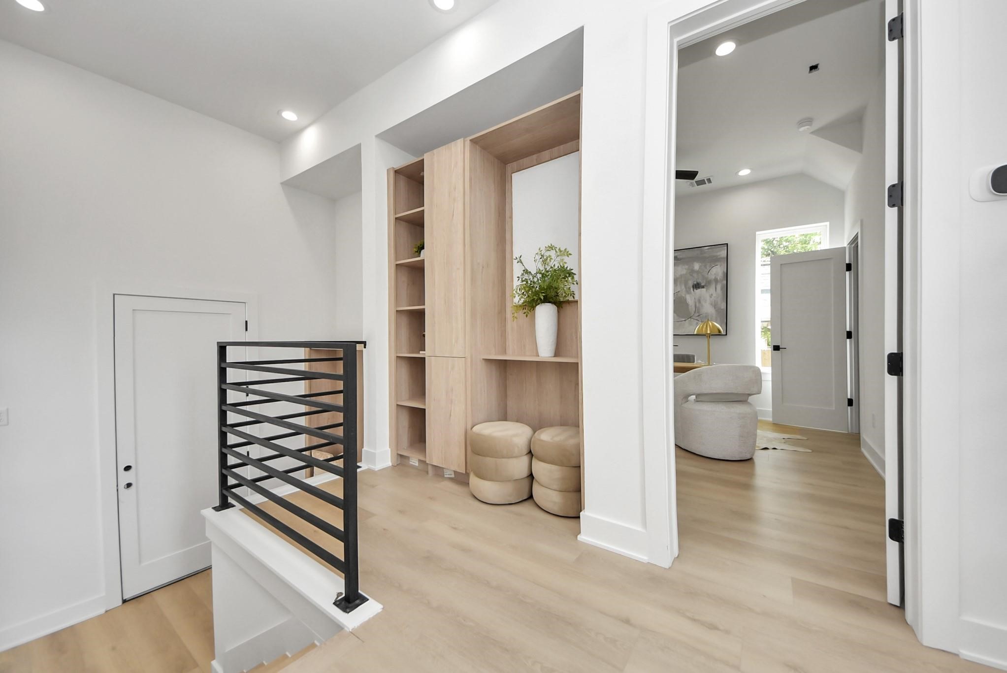 Upper landing showcasing light wood flooring, built-in storage, and access to the adjacent office.