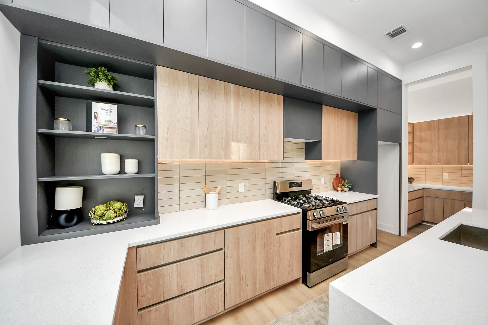 Bright kitchen with expansive windows, quartz countertops, open display shelving, and stainless steel appliances.