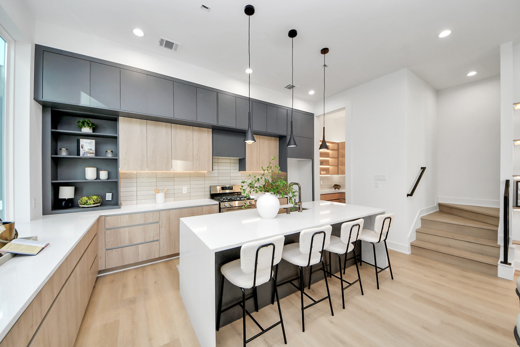 Modern kitchen featuring an oversized waterfall island with seating for four and sleek two-tone cabinetry.