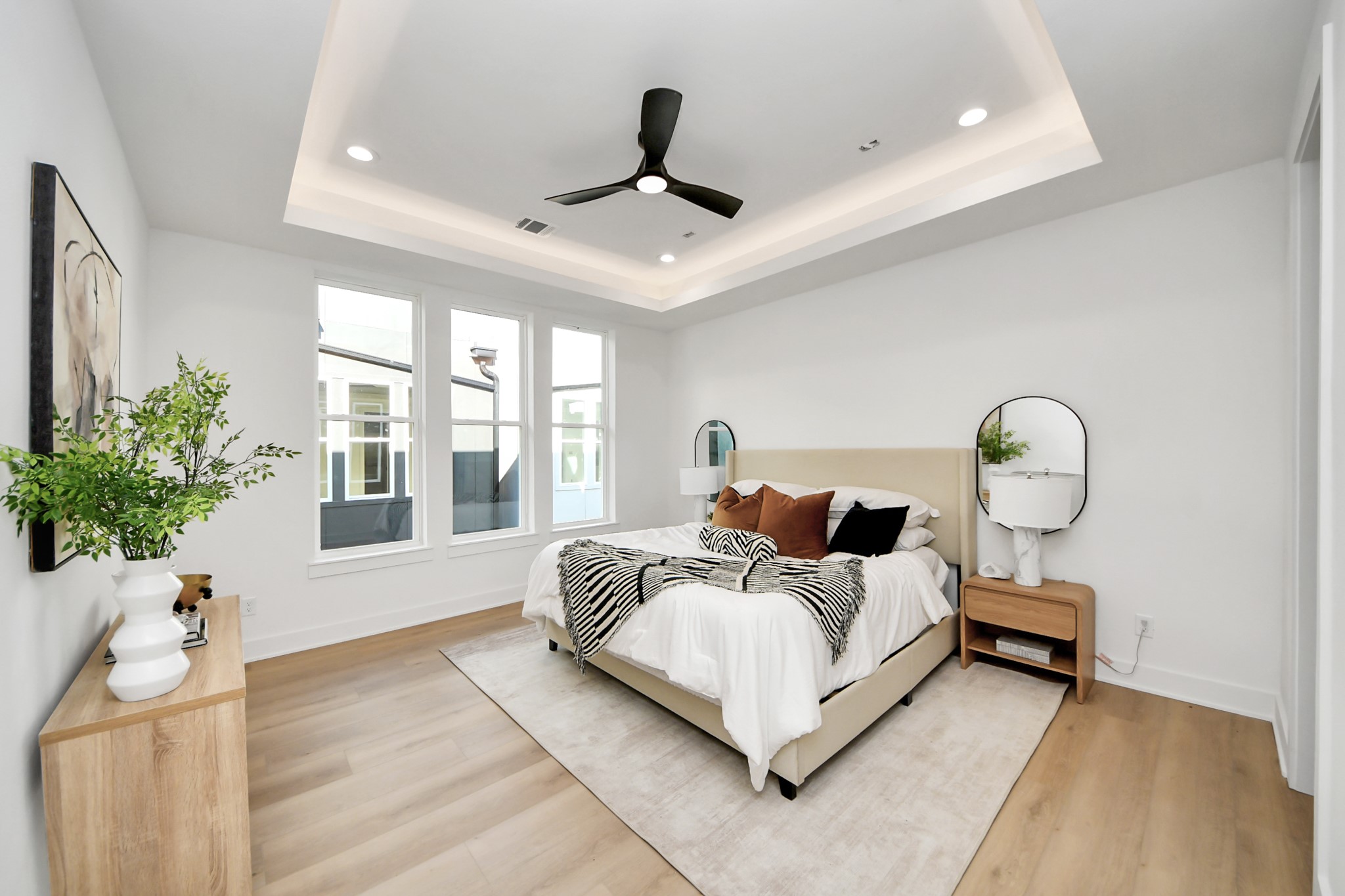 Primary bedroom located on the third floor with a tray ceiling and large windows.