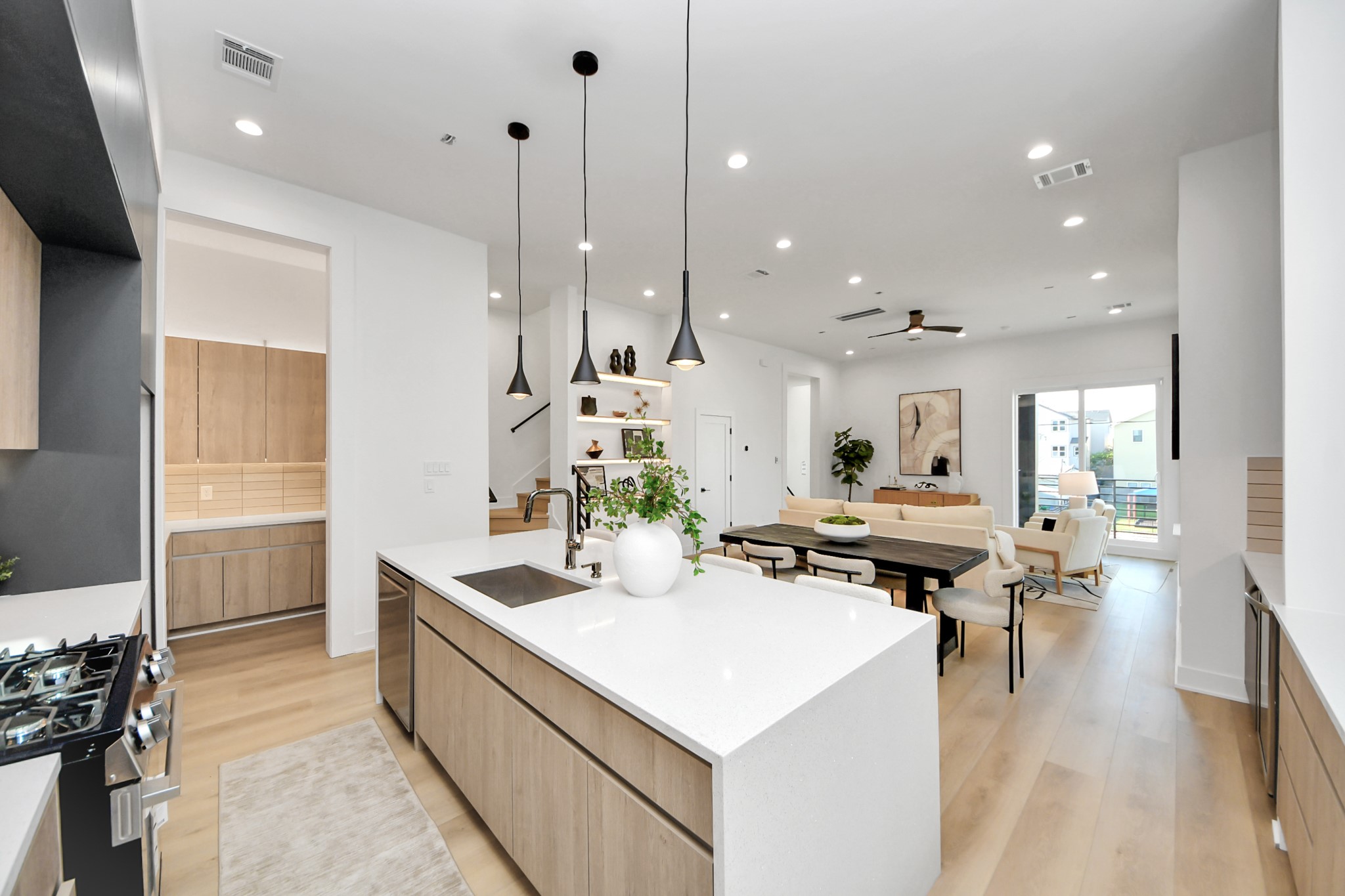 Chef-inspired kitchen featuring a gas range, large island with sink, pendant lighting, and walk-in pantry.