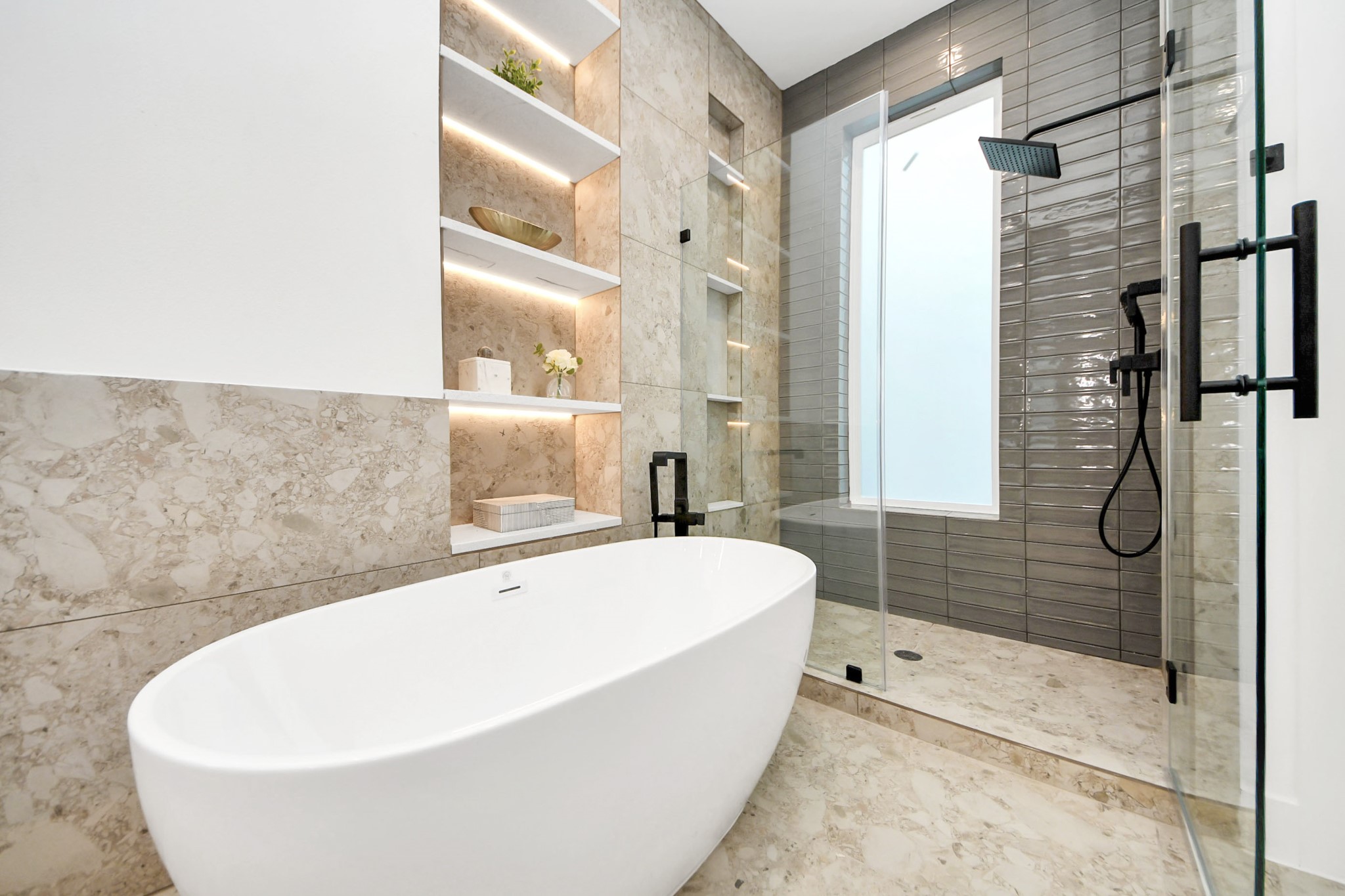 Primary bathroom featuring a freestanding tub, glass-enclosed shower, and built-in shelving.