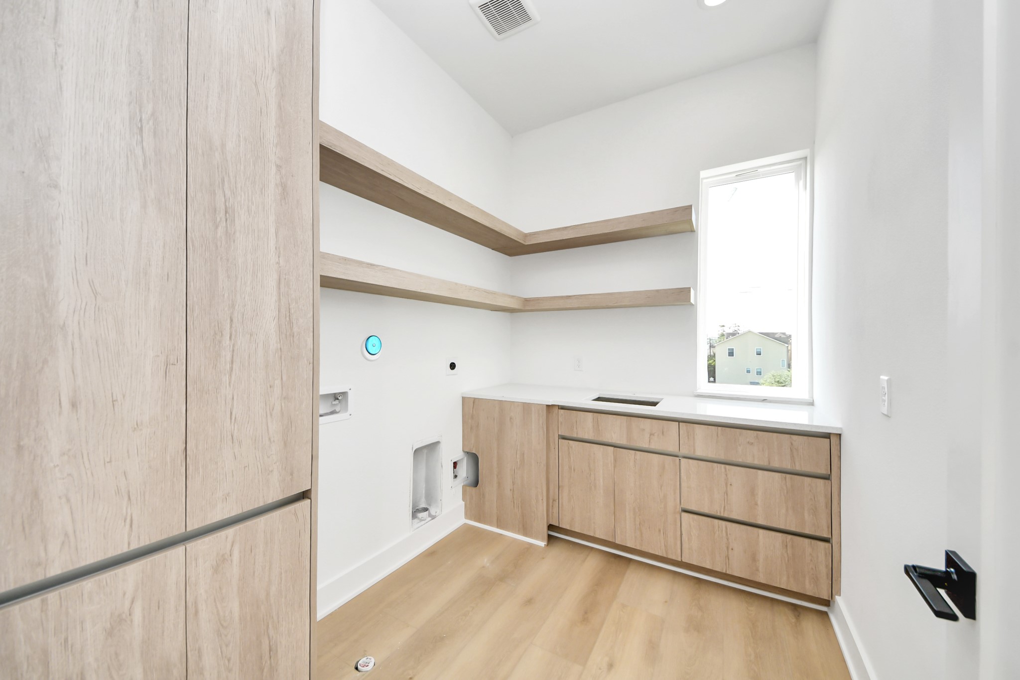 Third-floor laundry room with built-in cabinetry, shelving, and a utility sink.