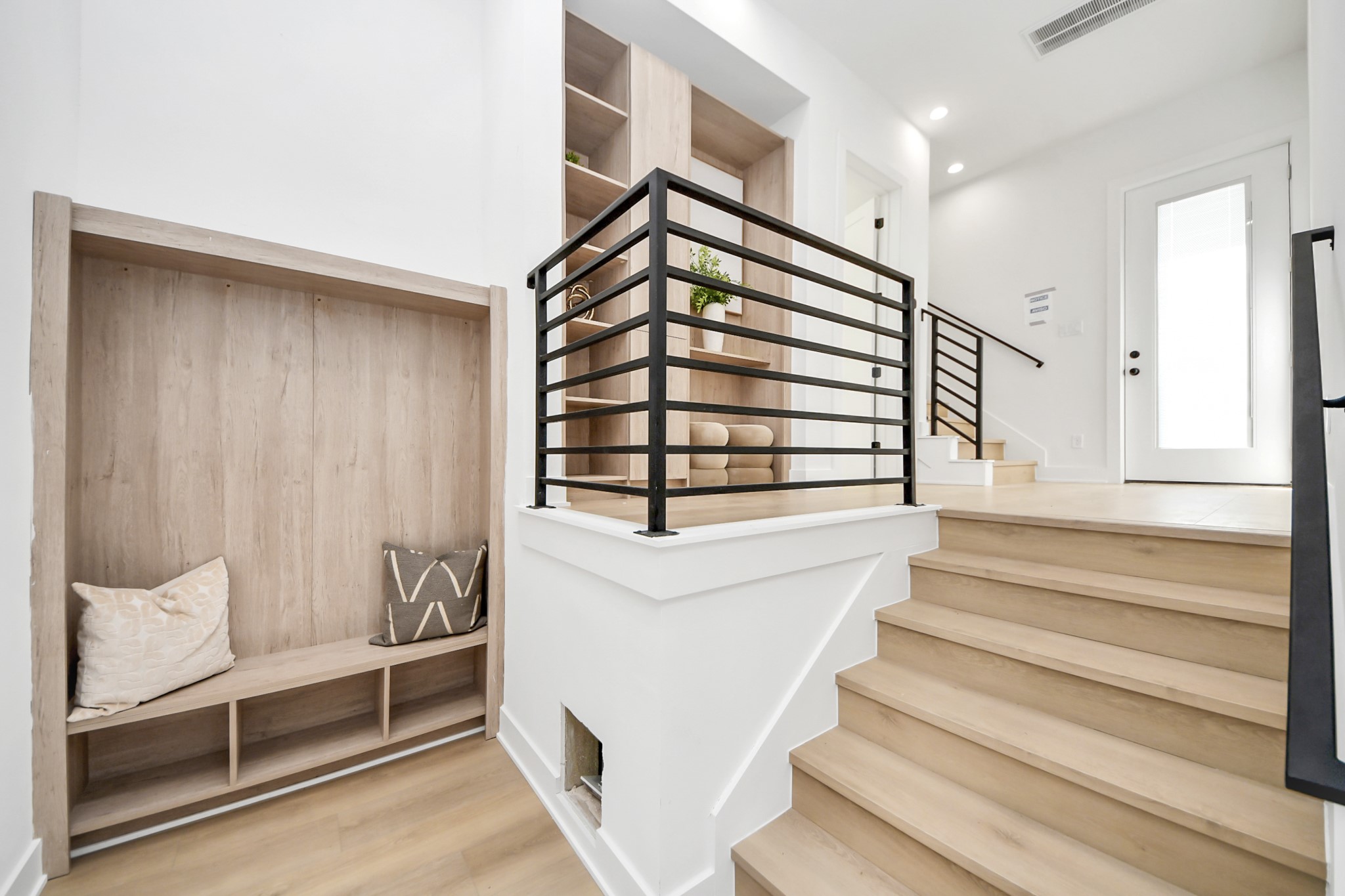 Stylish stair landing featuring sleek black railings and custom built-in storage.