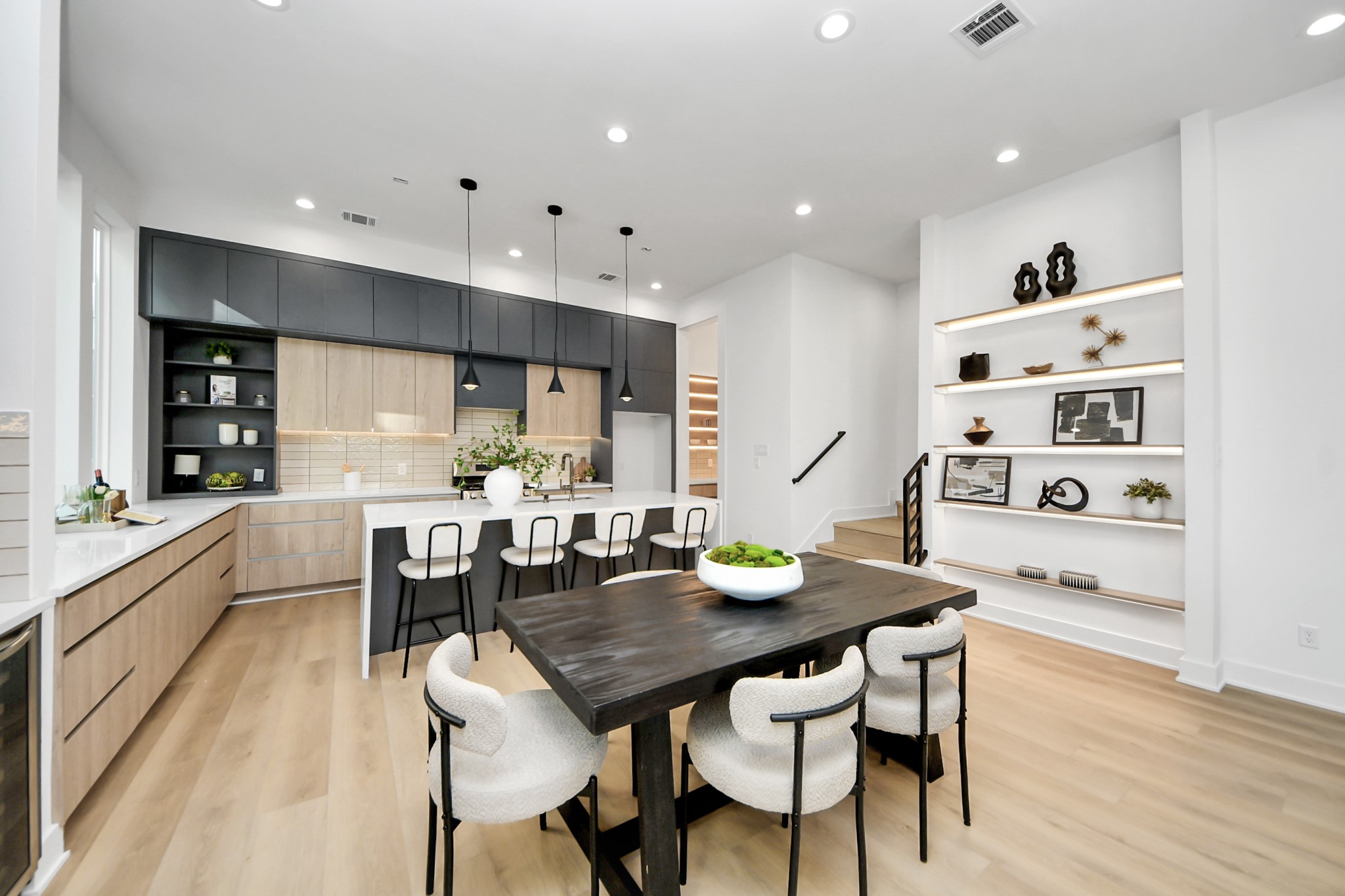Second-floor kitchen area featuring custom display shelving, light wood stairs, and easy access to the powder room.