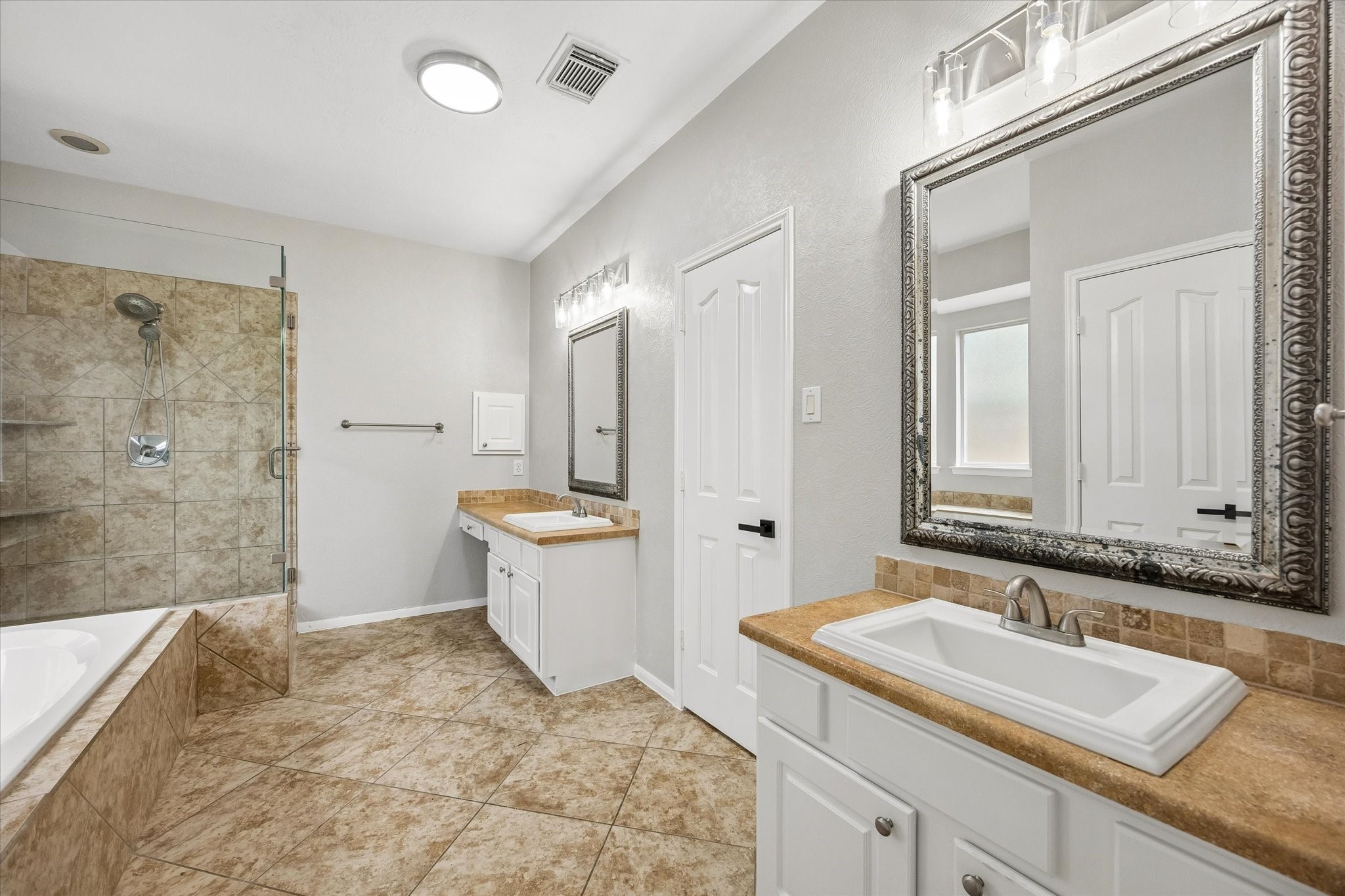 The primary bathroom features dual vanities, a soaking tub, a walk-in shower, and ample storage.