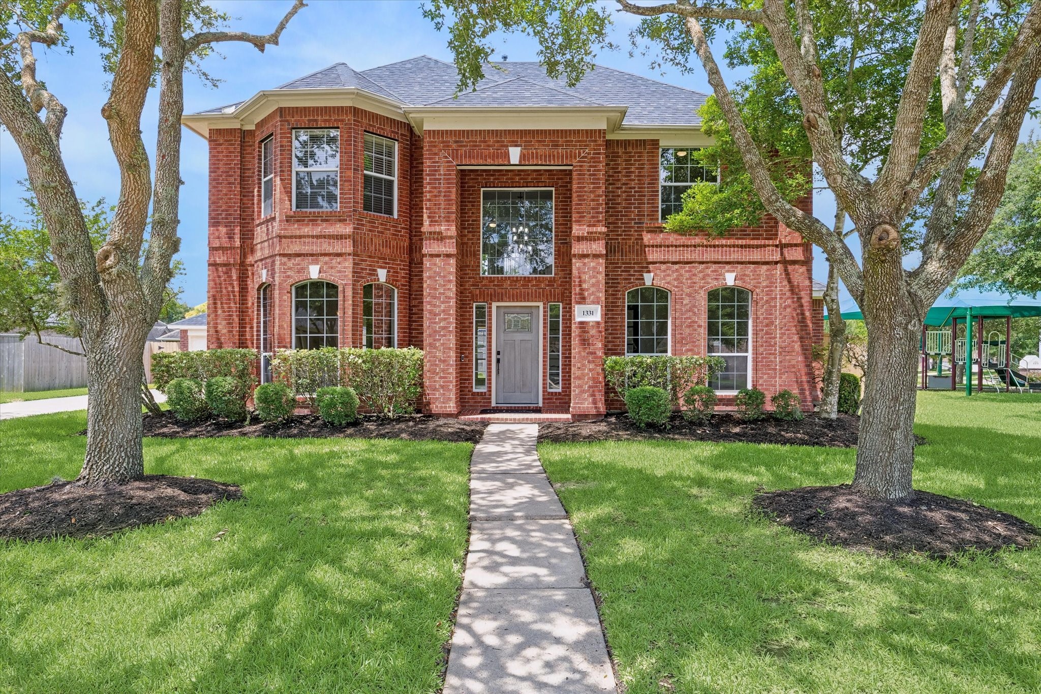 A stately brick faade, mature oak trees, and professional landscaping create exceptional curb appeal.