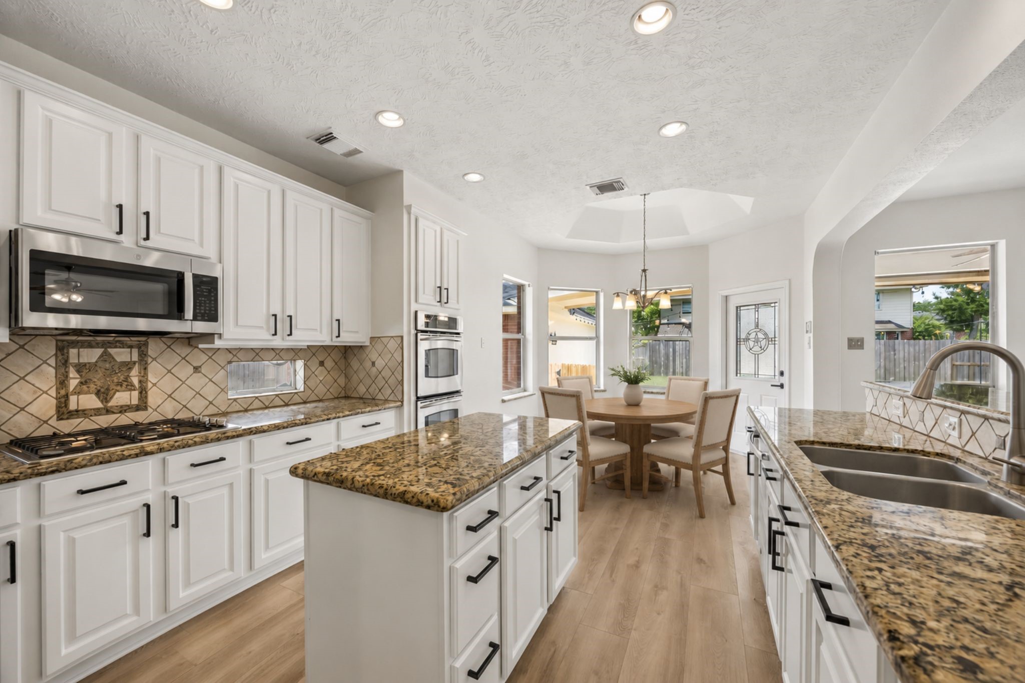 Another view of the kitchen highlights the generous prep space, gas cooktop, double ovens, and open layout.