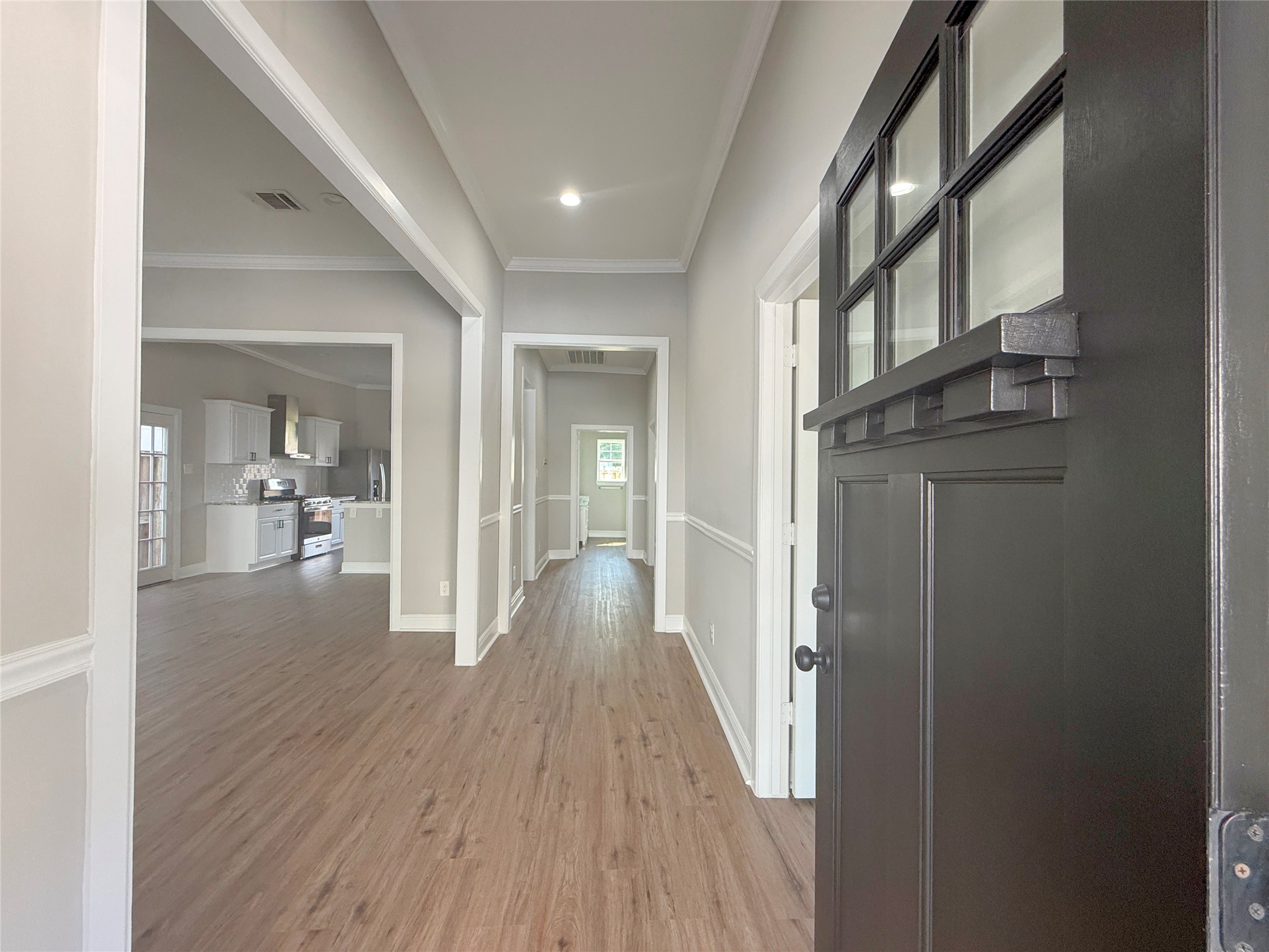 Welcoming foyer featuring NEW flooring, crown molding, chair rail accents, and recessed lighting, with an open view into the kitchen and adjoining living areas.