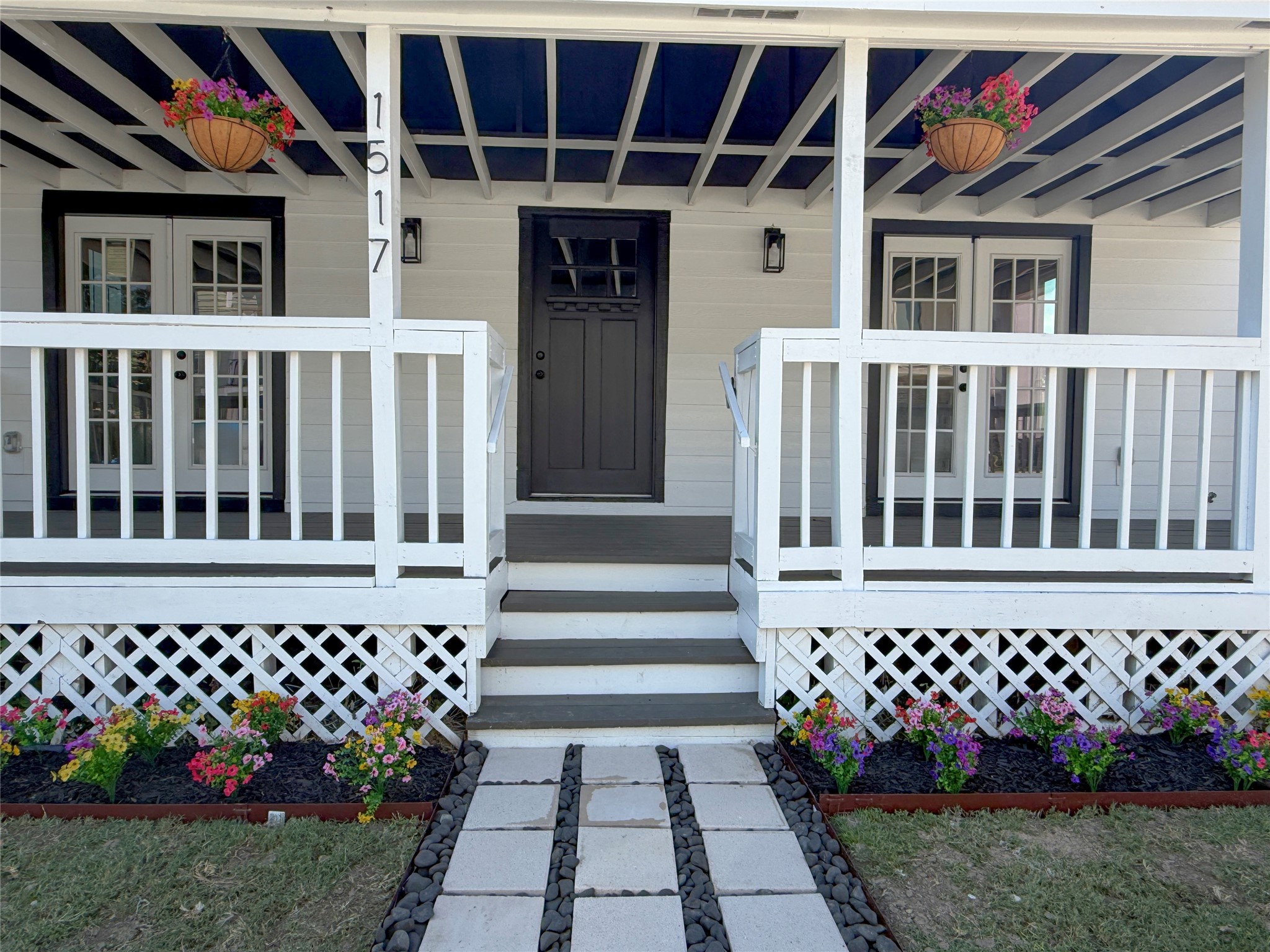 Centrally positioned entry steps lead to a distinctive front door, flanked by French doors on both sides. A decorative paver walkway completes the welcoming entrance.