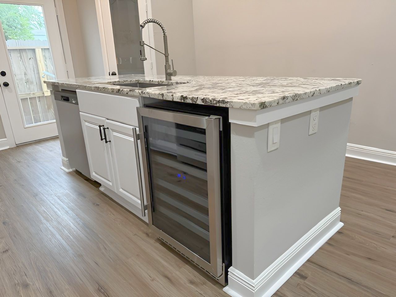 Impressive multifunctional island features a farmhouse-style sink, NEW stainless steel dishwasher, NEW built-in wine refrigerator, and convenient electrical outlets.