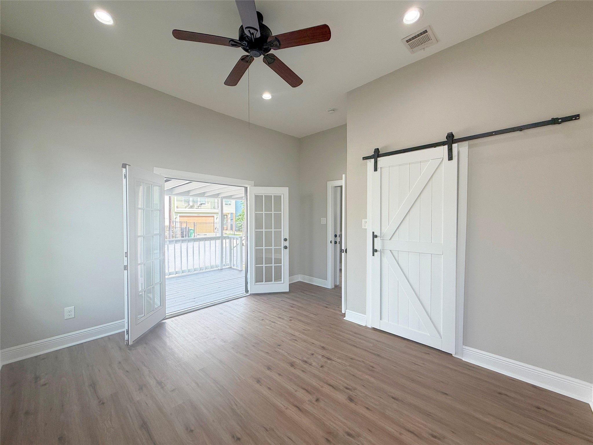 Beautiful French doors open directly onto the expansive covered front porch, inviting natural light into this charming bedroom. High ceilings and a sliding barn door closet complete the space.