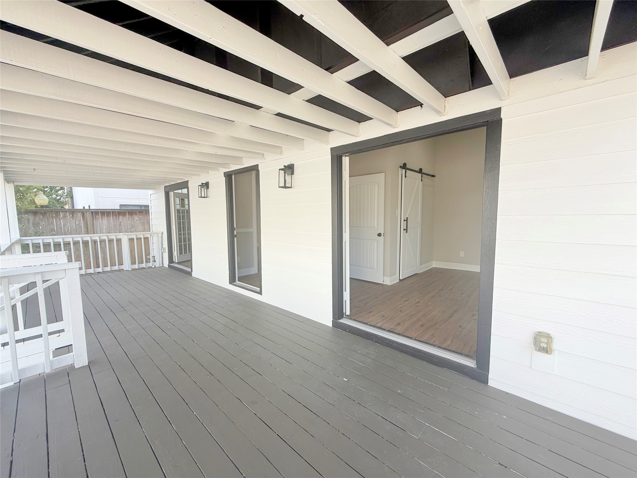 Another perspective reveals the porch's impressive length and direct access to the secondary bedroom through French doors. The covered design and classic railing add architectural character to this inviting outdoor retreat.