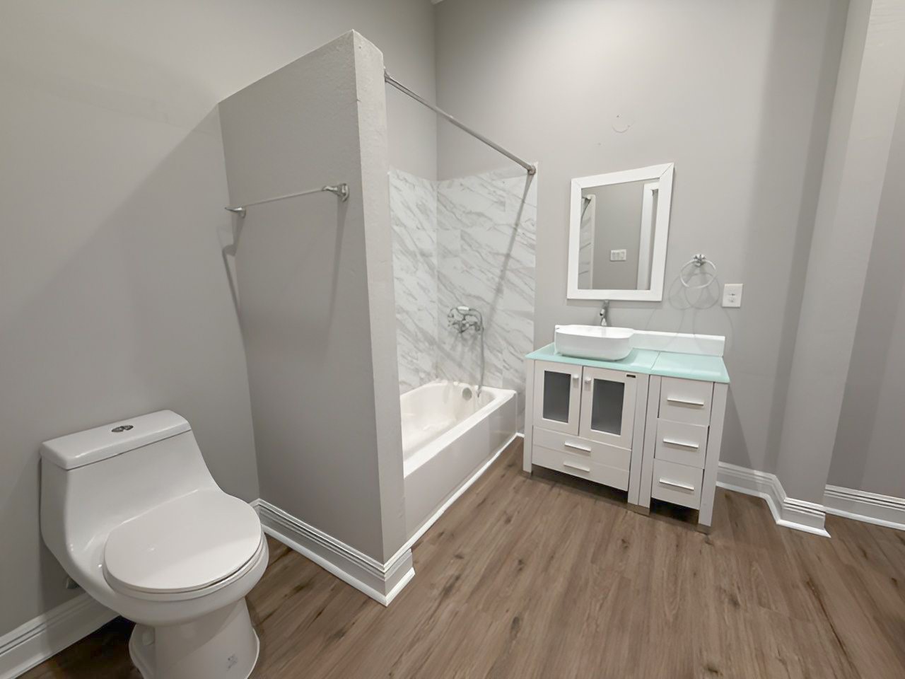 Primary bathroom features a tub/shower combination with marble-look tile surround, contemporary vessel sink vanity, and modern fixtures.