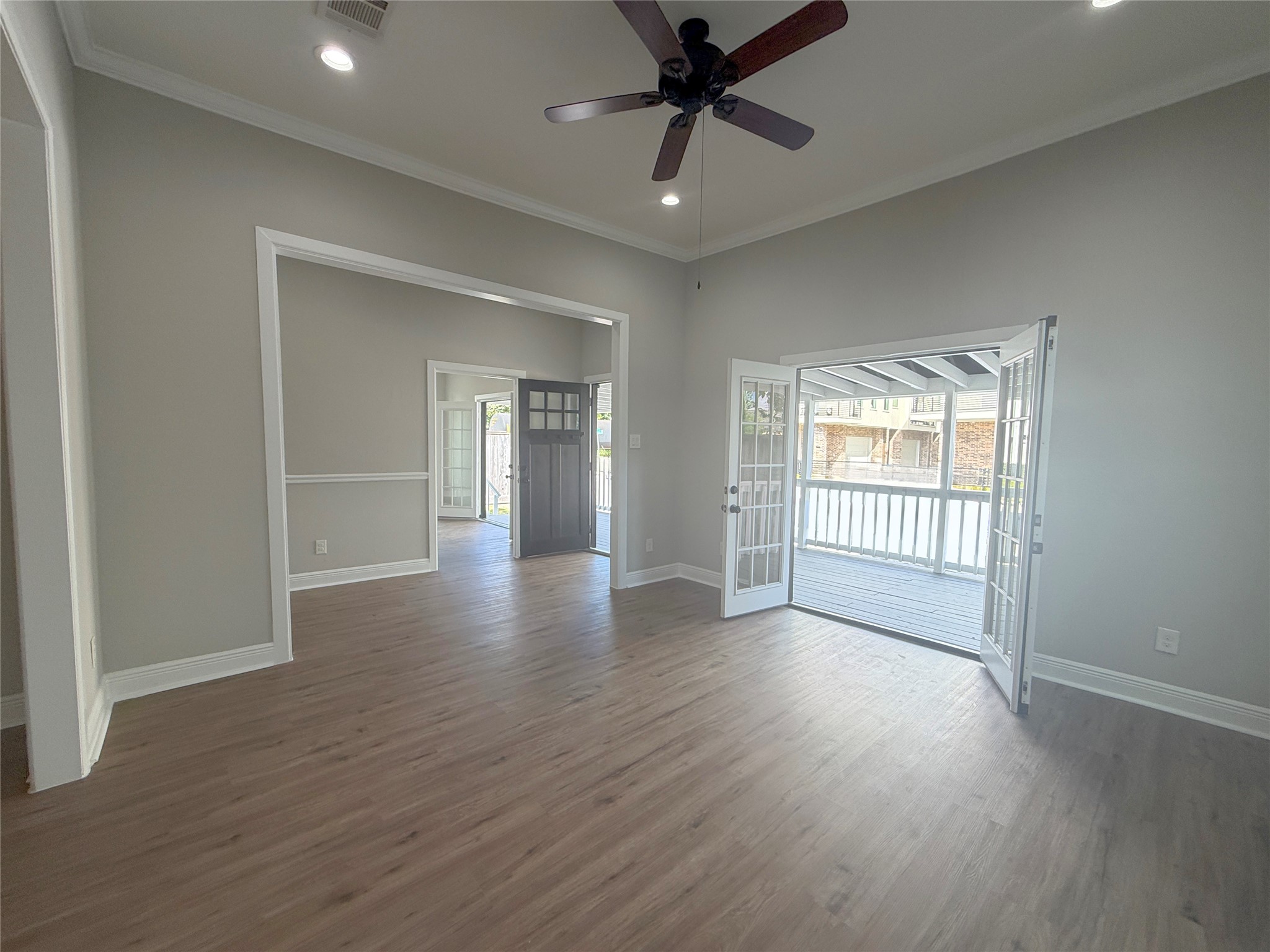 The inviting living room features high ceilings, recessed lighting, and an open connection to the adjoining living spaces. French doors create an impressive transition to the home's spacious covered front porch.