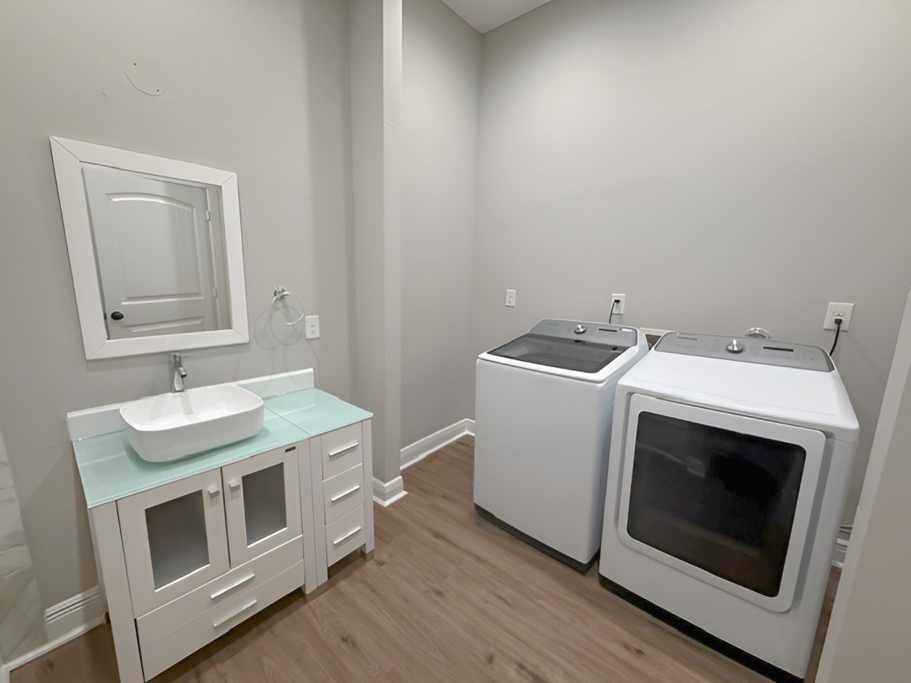 Conveniently located within the primary bathroom, the laundry area accommodates a full-size washer and dryer alongside a contemporary vanity with additional storage.