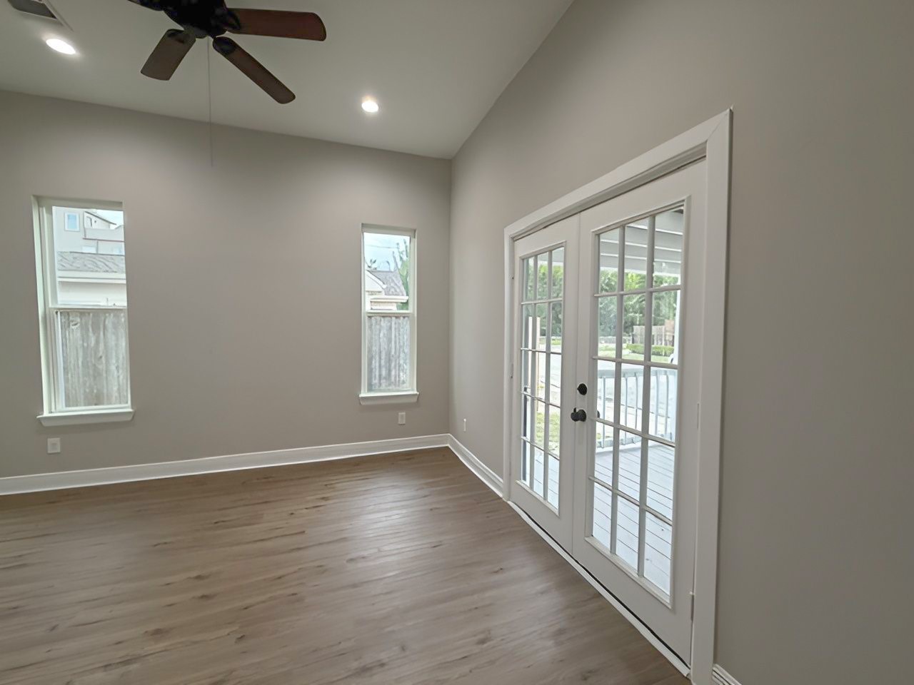 Bright secondary bedroom offers high ceilings, recessed lighting, and French doors opening to the covered front porch, creating an inviting connection to the outdoors.