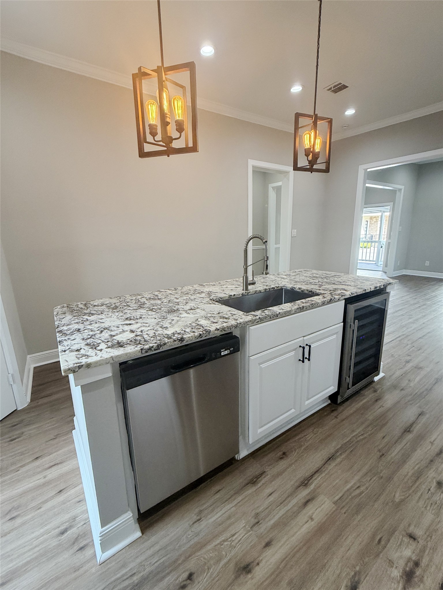 Expansive granite-topped island offers generous preparation space, an undermount sink with a commercial-style pull-down faucet, and distinctive pendant lighting.