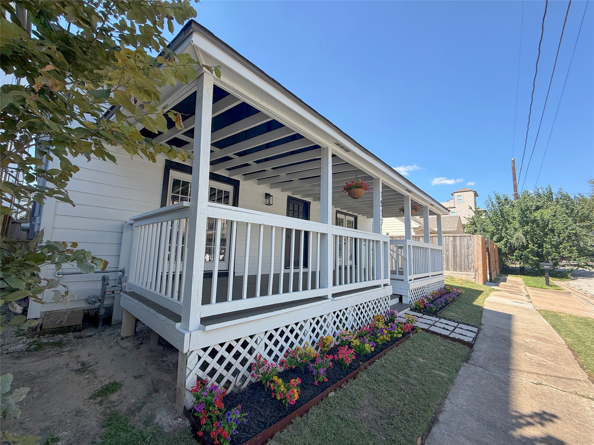 Attractive side perspective highlighting the home's classic exterior, decorative latticework, and colorful flower beds lining the porch.