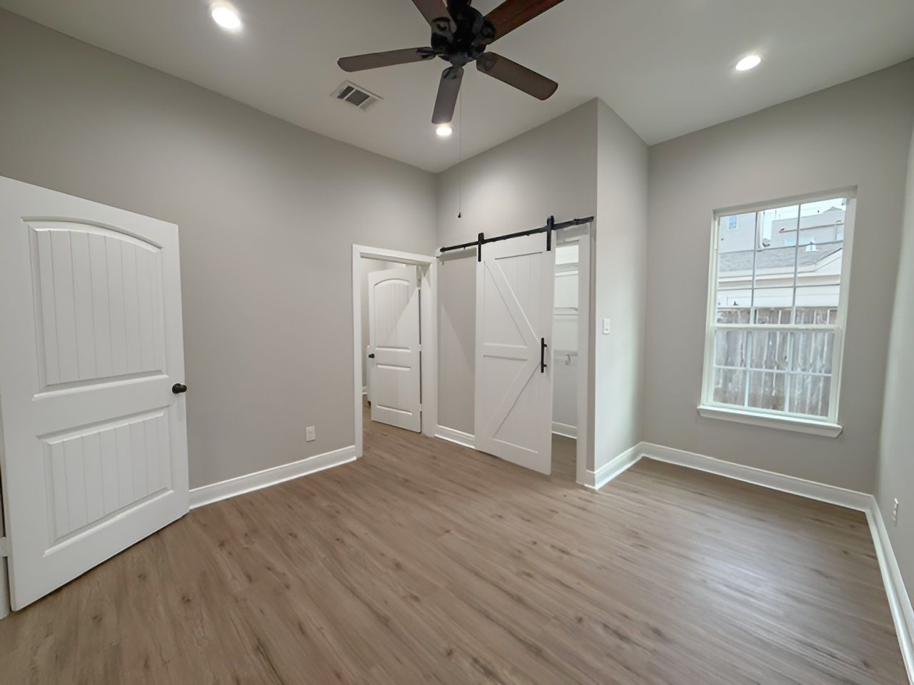 Another perspective highlights the room's generous dimensions, natural lighting, and stylish barn door leading to the adjoining closet.