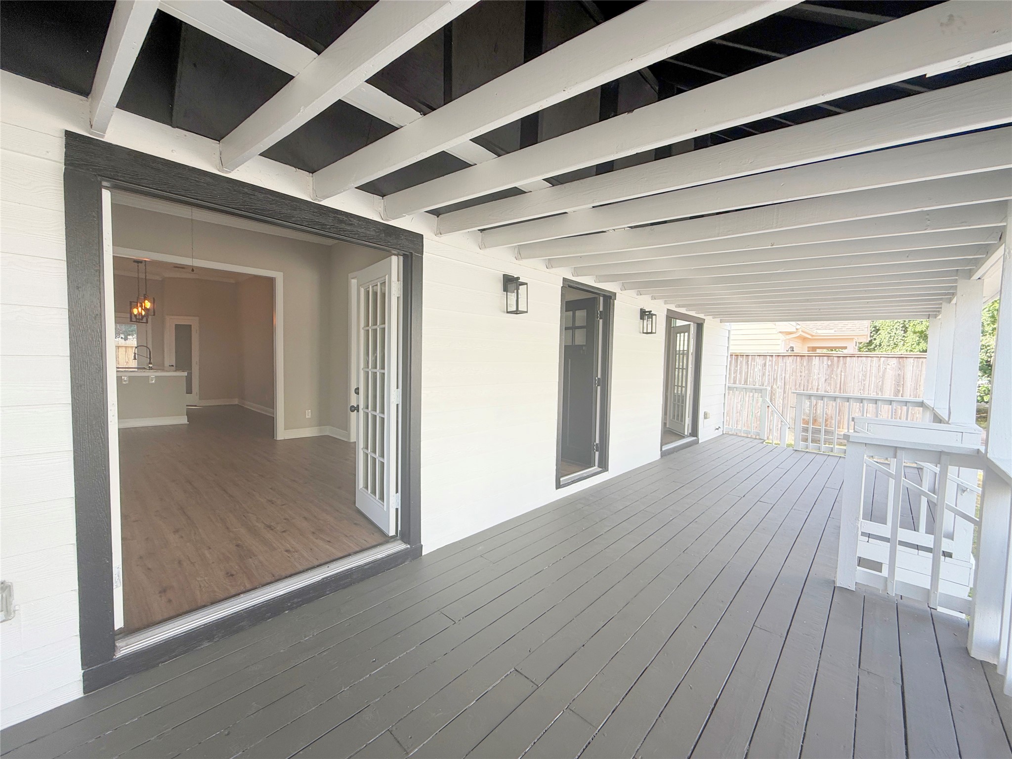 This expansive covered porch showcases exposed ceiling beams, contrasting trim, and multiple entrances to the home. The generous layout provides wonderful possibilities for outdoor seating and relaxation.