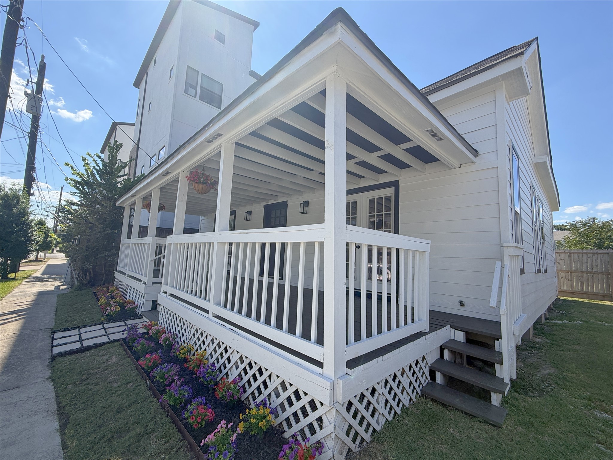 Angled view showcasing the home's expansive covered porch, crisp white railings, and convenient side access.