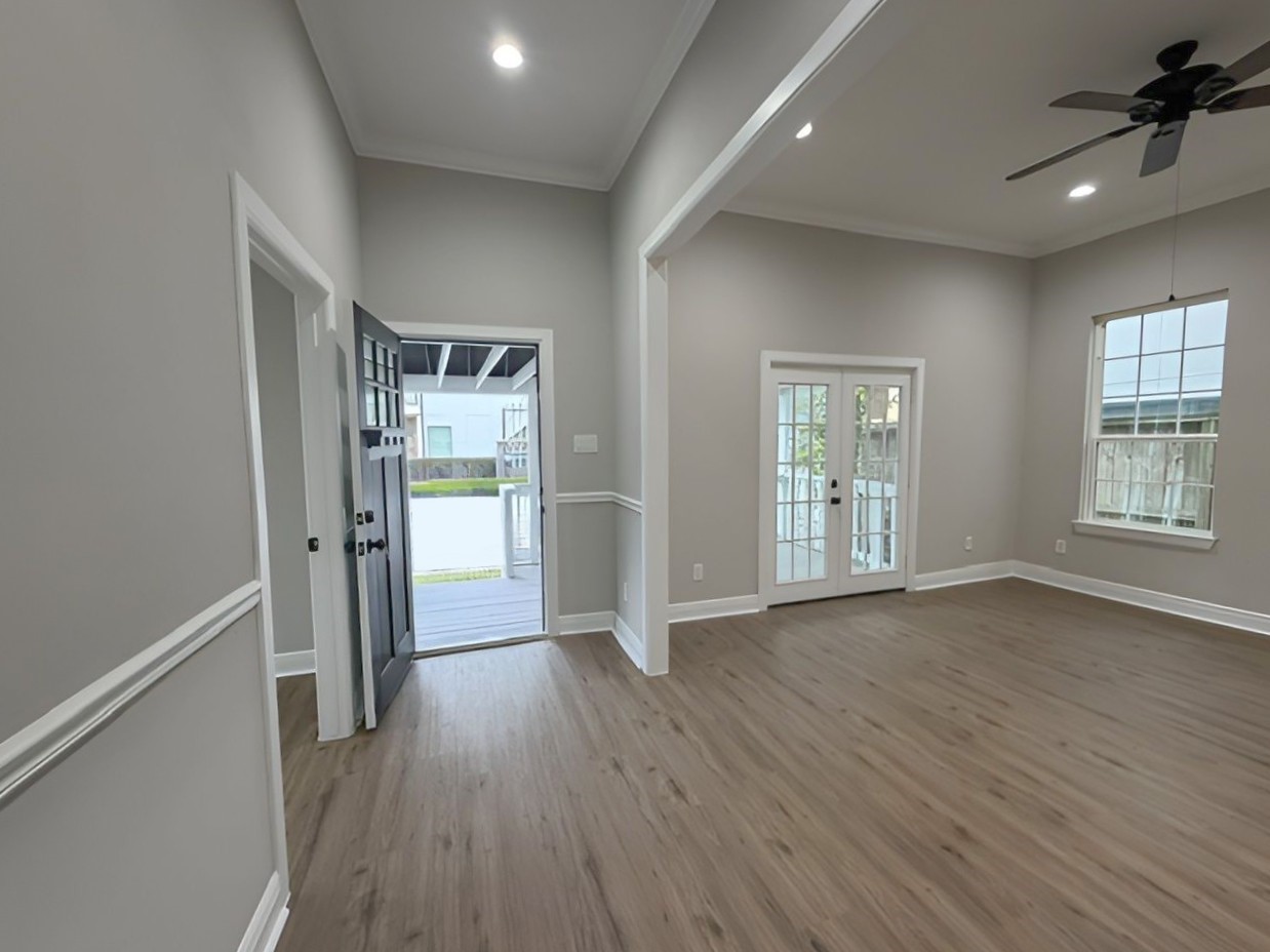 Reverse perspective highlights the spacious living area, abundant natural light, and French doors opening onto the expansive covered front porch.