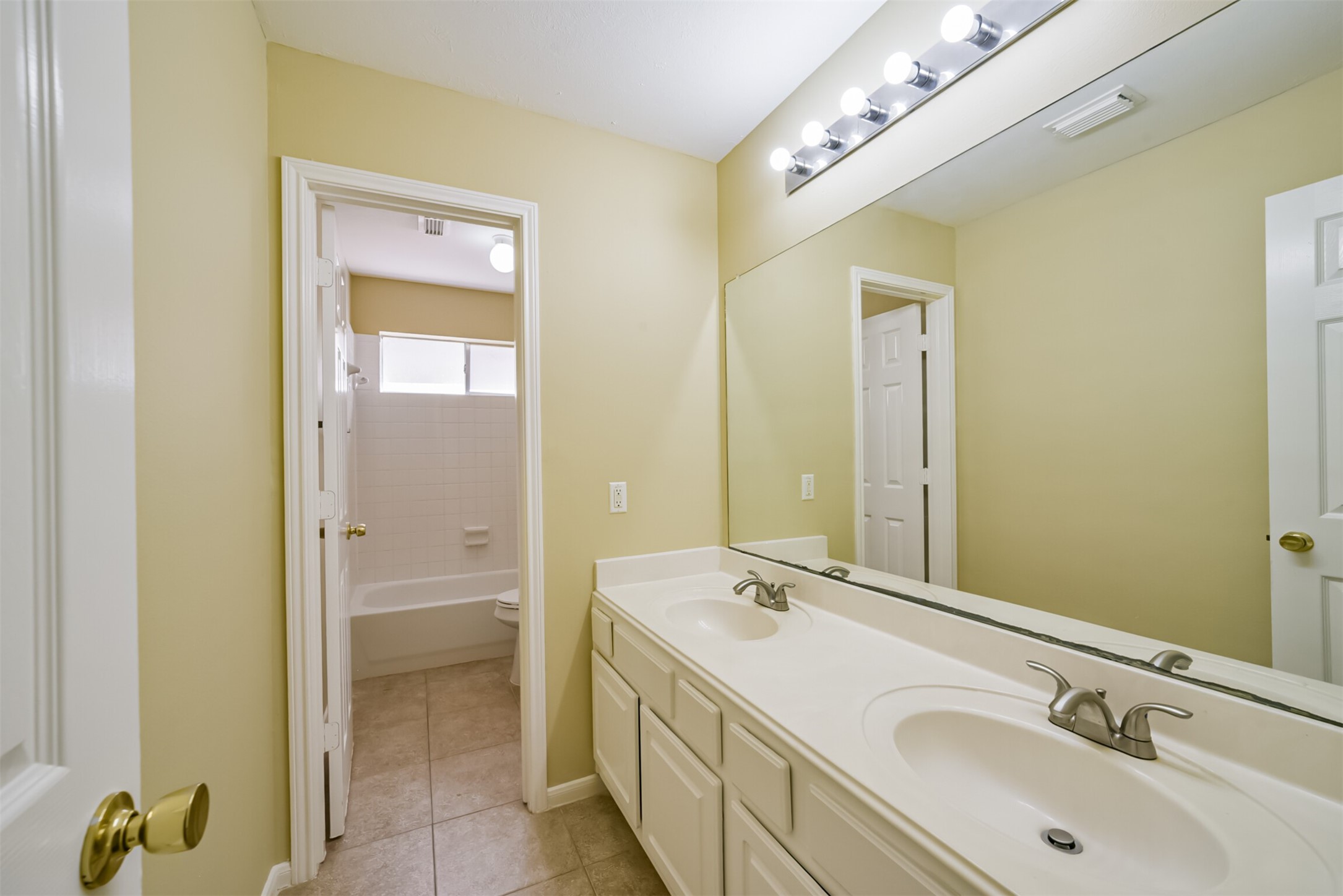 Secondary full bath with dual sinks and a separate tub/shower area with its own door.